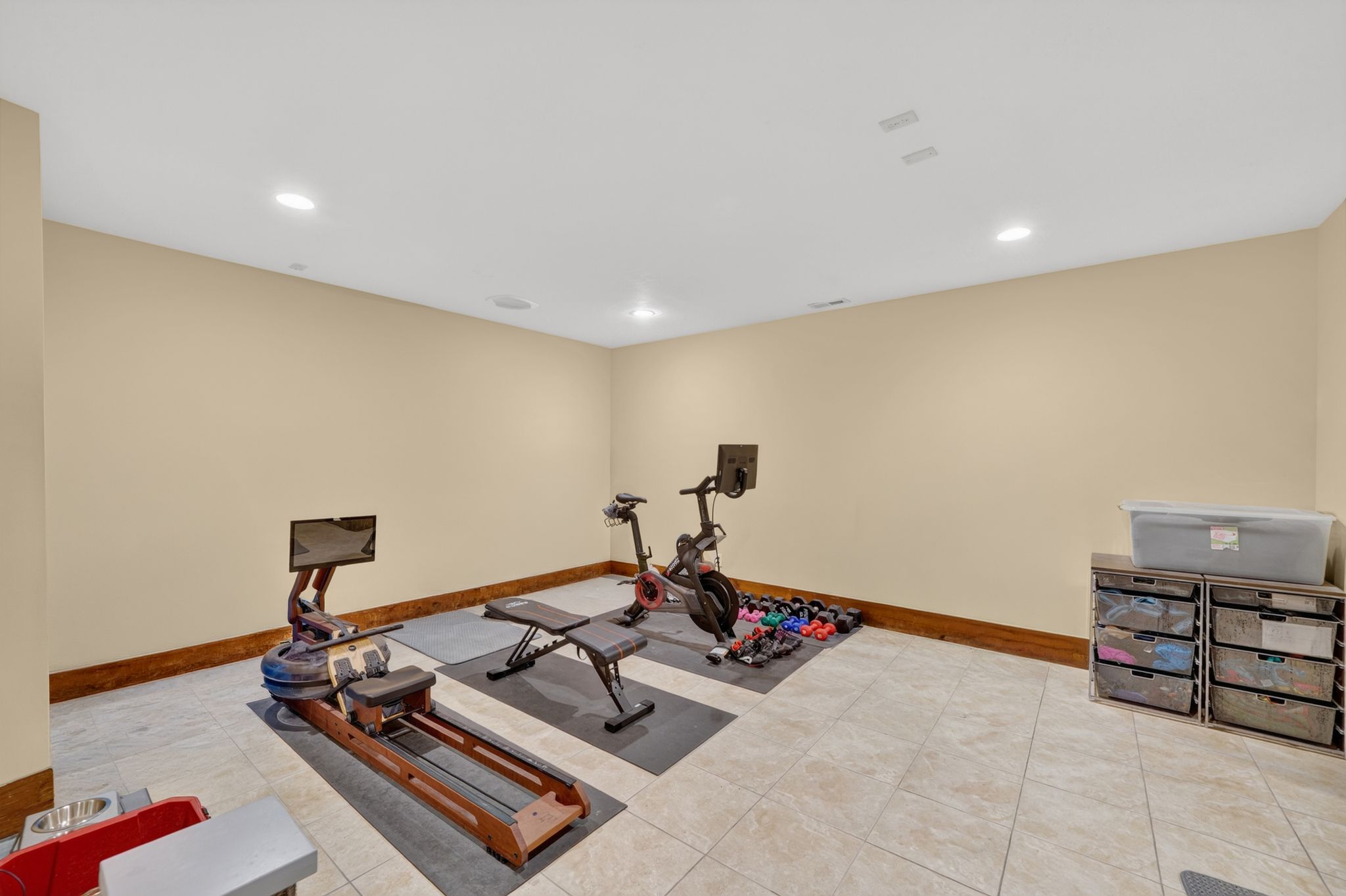 Spacious room featuring neutral wall tones, recessed lighting, tile flooring, and a substantial wood baseboard