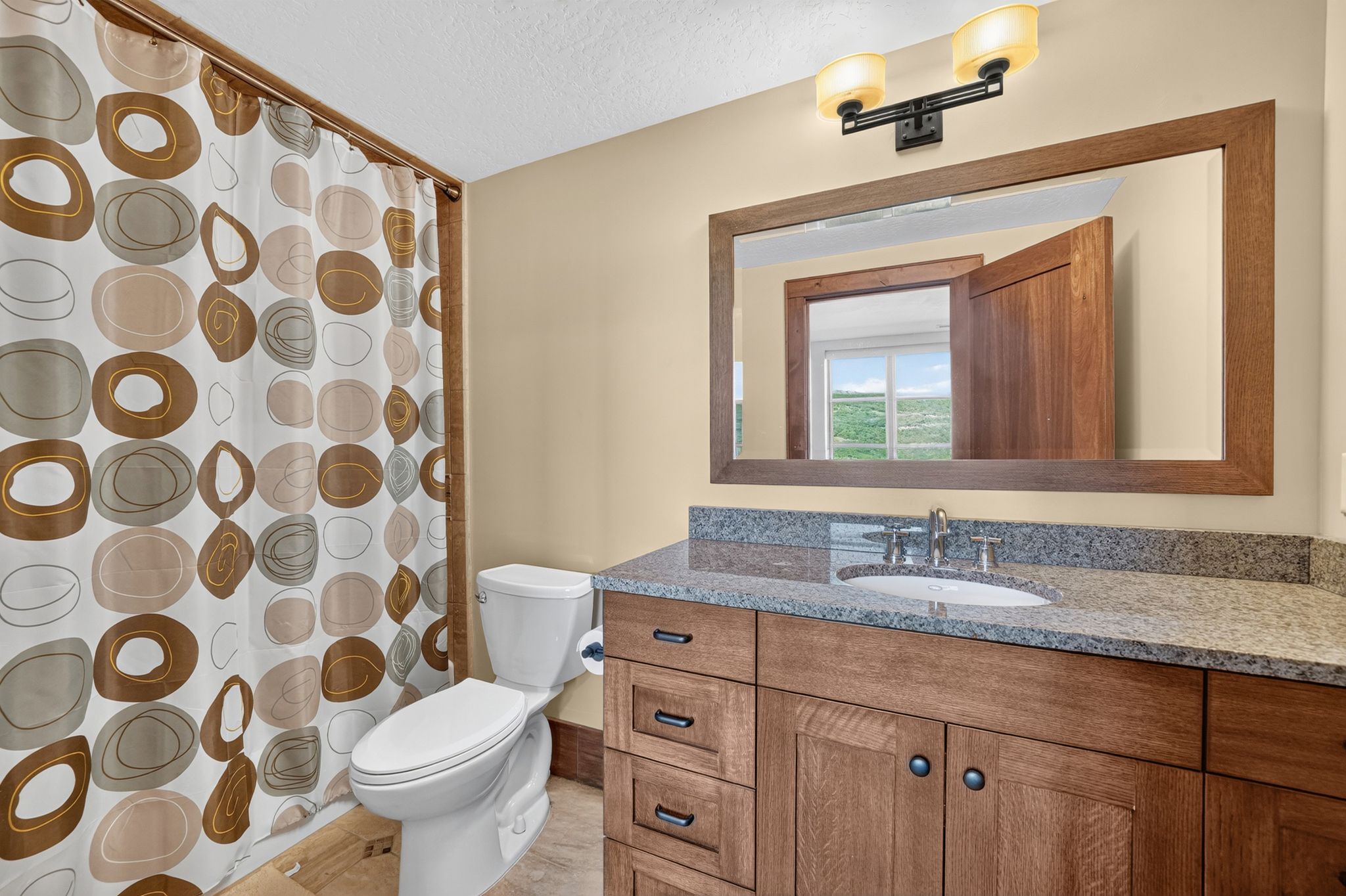Wood-finish vanity with a granite-style countertop and undermount sink