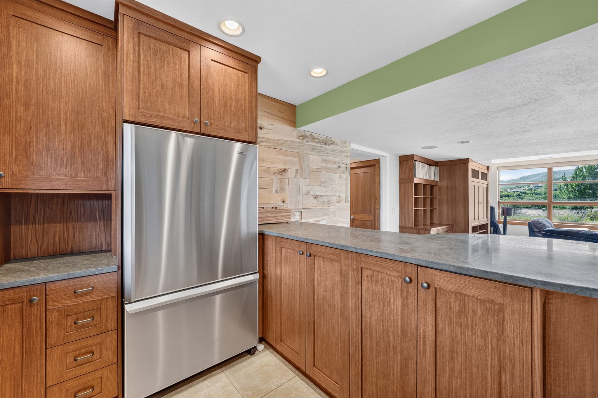 Stainless steel refrigerator integrated within custom wood cabinetry with stone countertops