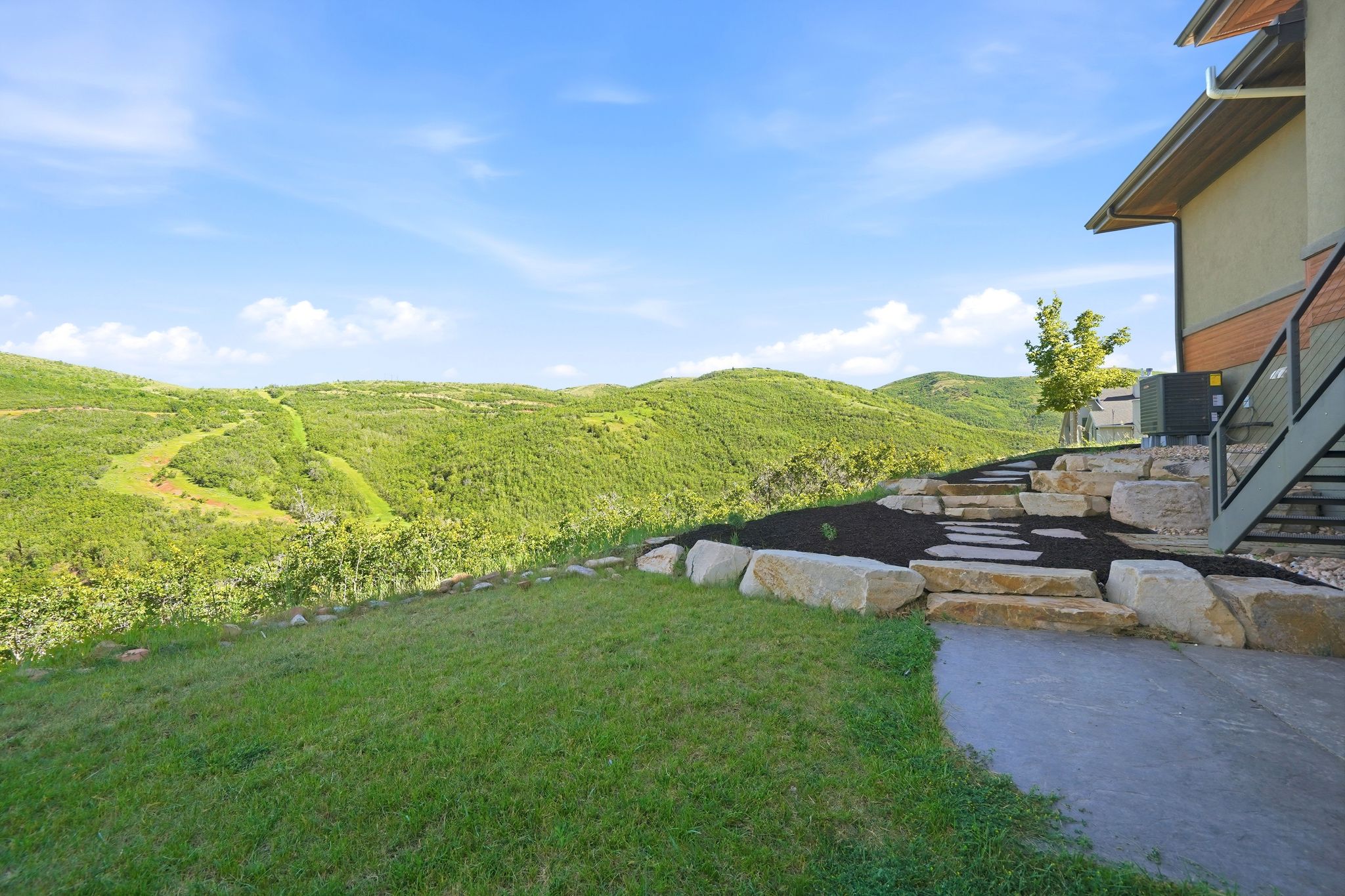 Expansive hillside property featuring a manicured lawn and stone step pathway