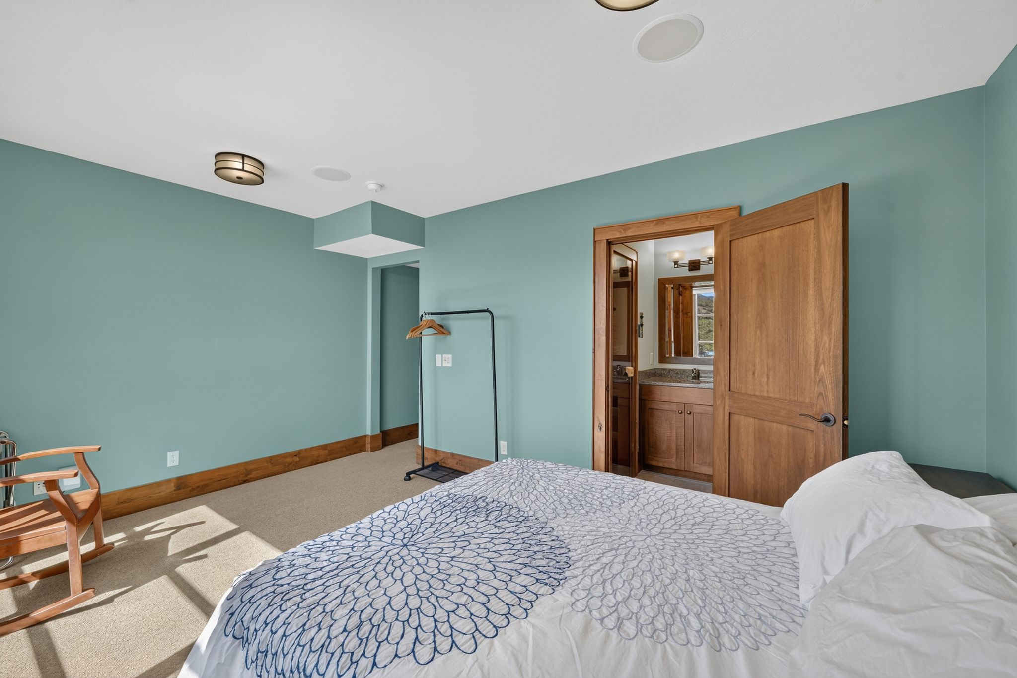 Carpeted room with light teal walls and wood trim