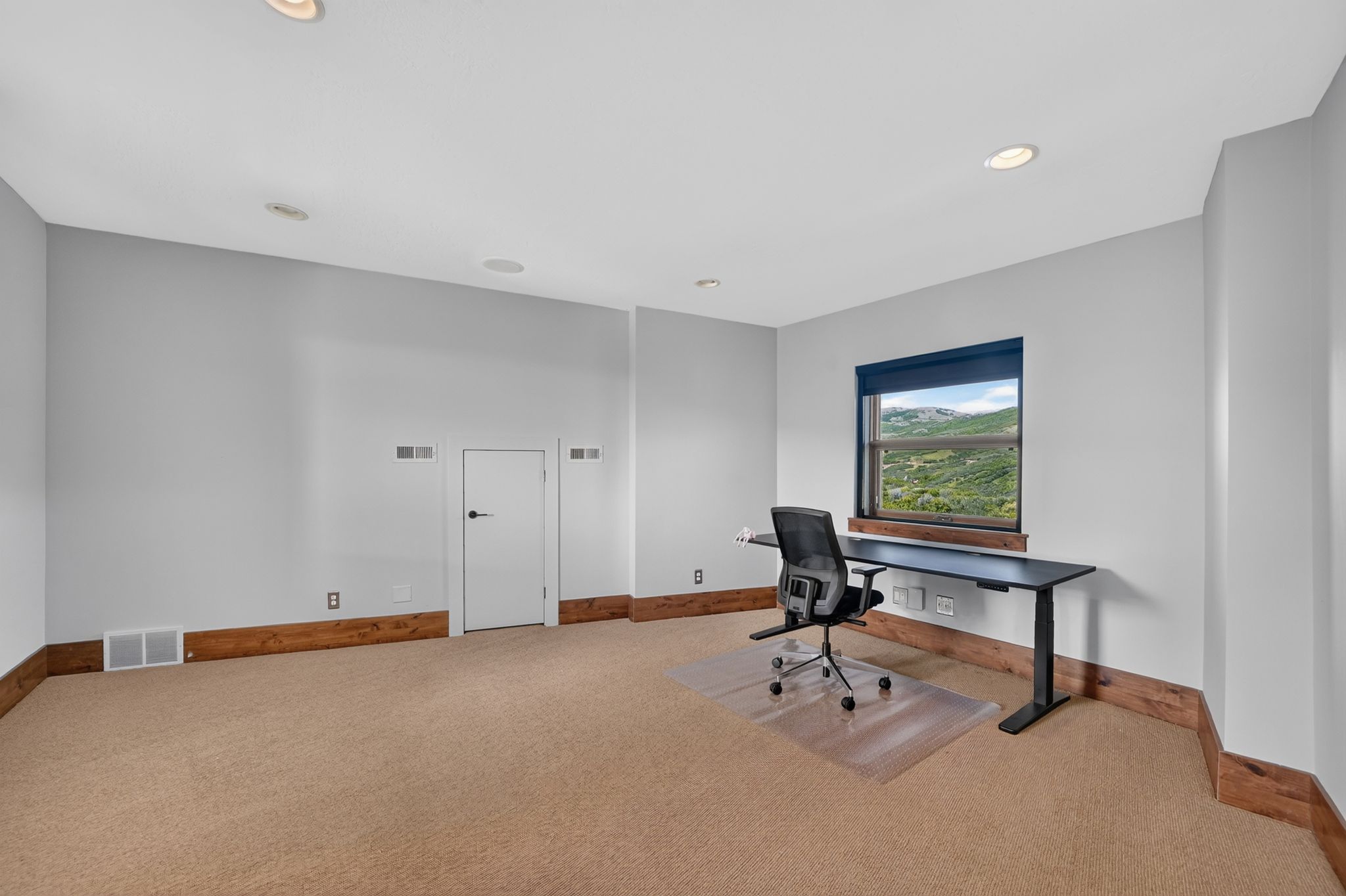 Carpeted room with recessed lighting and a window featuring a mountain backdrop