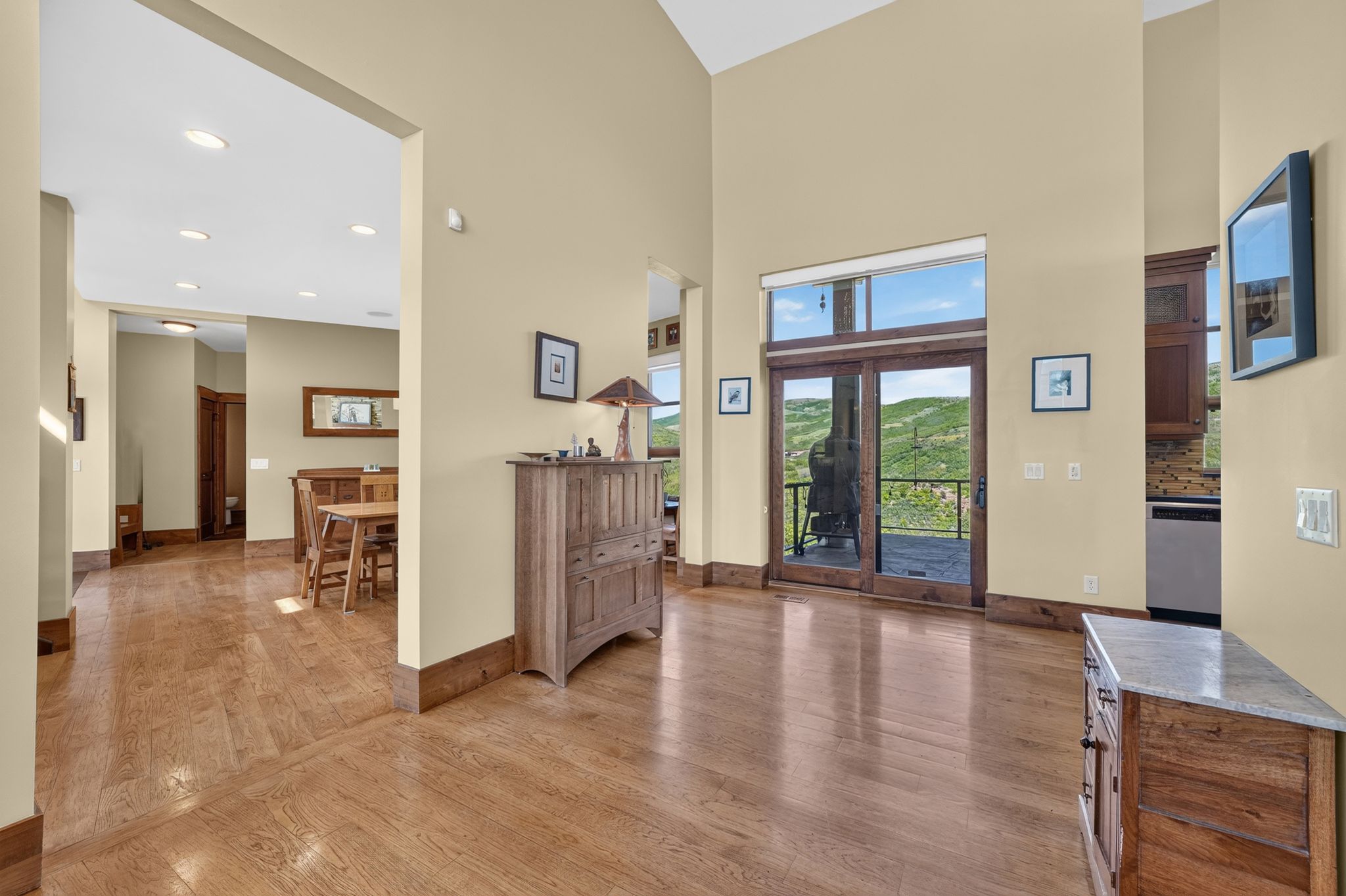 Hardwood flooring extending throughout the main living areas, featuring a dining space with recessed lighting and a full glass patio door