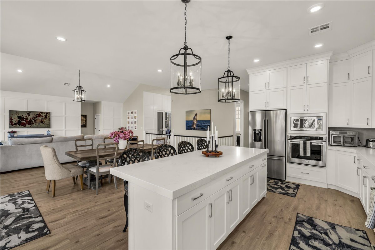 Kitchen featuring a large central island with white cabinetry, stainless steel appliances, and wood-finish flooring
