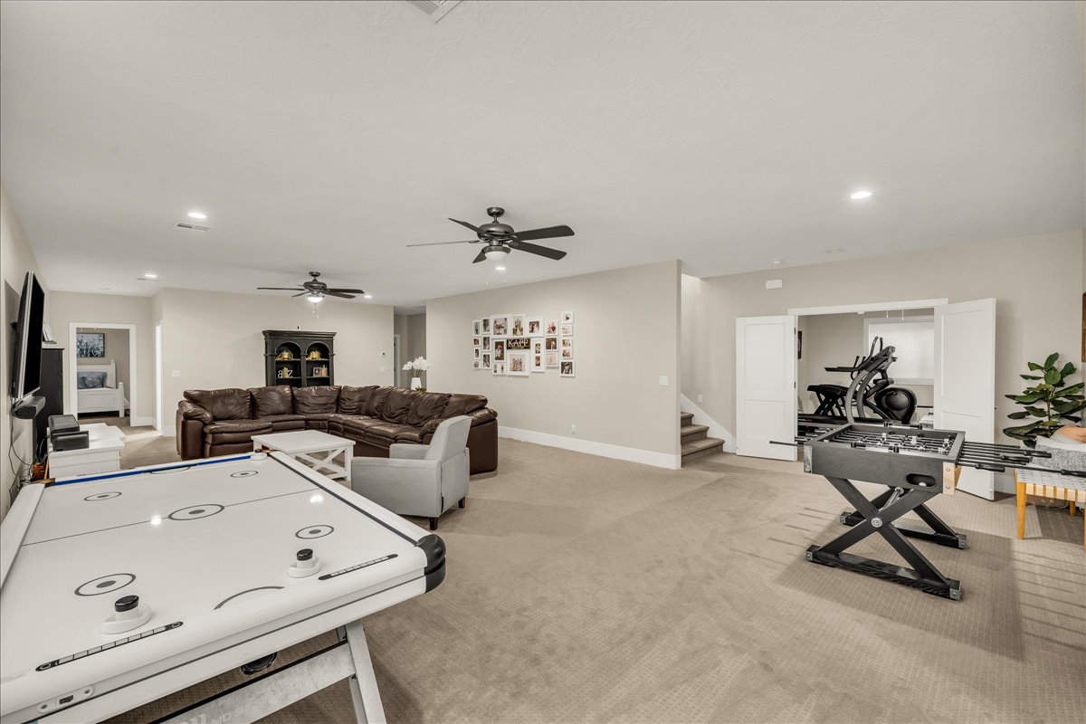 Spacious carpeted recreation area featuring recessed lighting and multiple ceiling fans