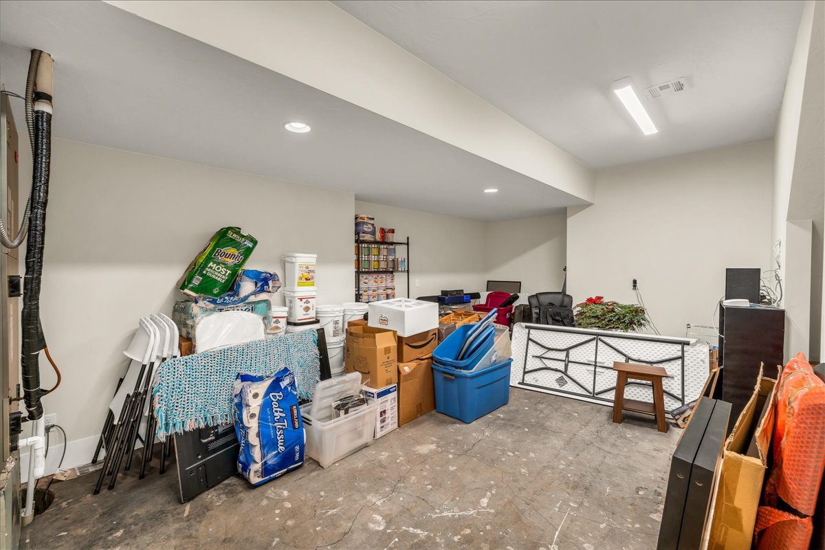 Unfinished basement area featuring painted concrete flooring, recessed lighting, and a fluorescent overhead light fixture