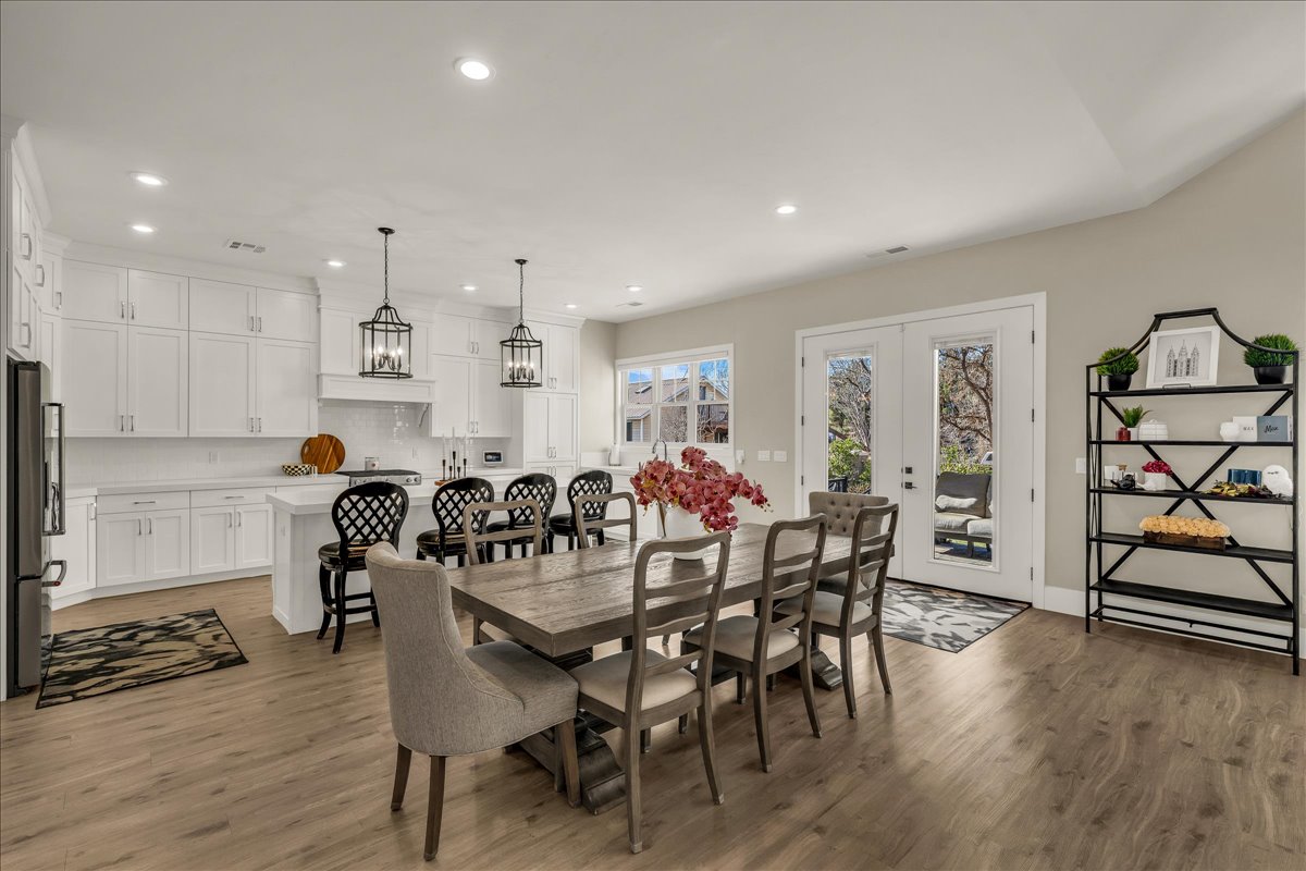 Open-concept kitchen and dining area featuring light wood-finish flooring, recessed lighting, and a white kitchen island with seating