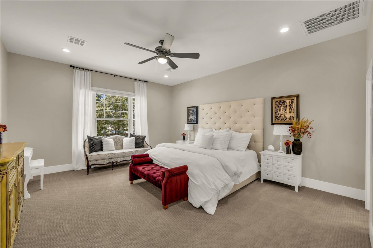 Spacious room featuring neutral-toned walls, recessed lighting, a ceiling fan, a large window with white curtains, and broad white baseboards