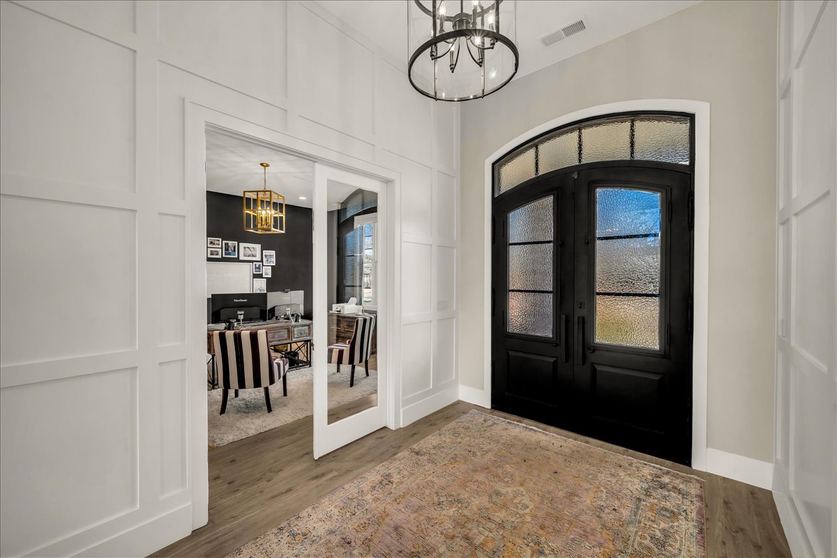 Grand entryway featuring double arched doors with opaque glass, a transom window, and a contemporary chandelier