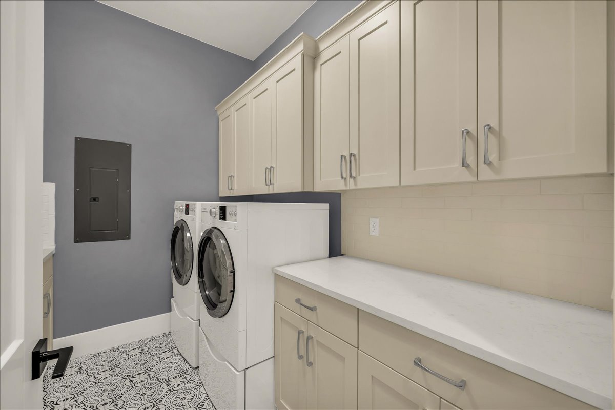 Laundry area featuring patterned floor tiles, white baseboards, and a dark blue accent wall