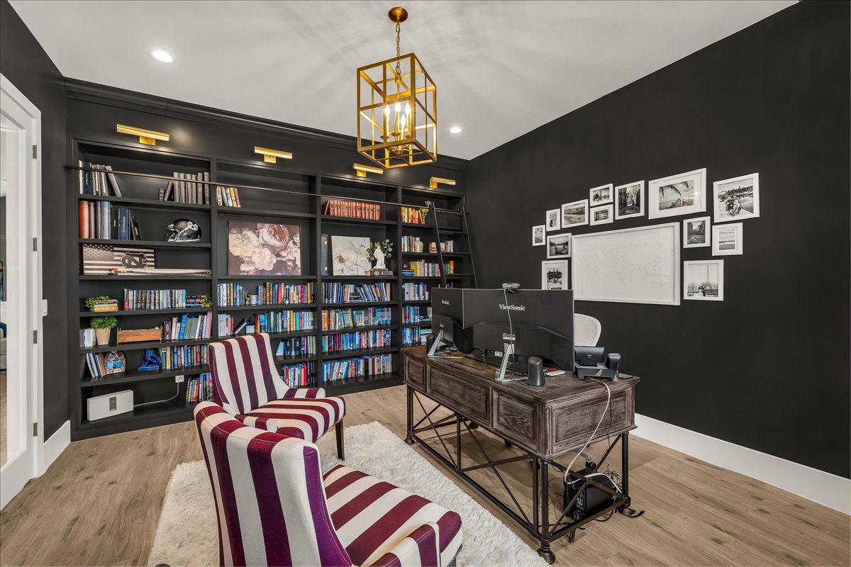 Dedicated room featuring extensive built-in shelving, wood-finish flooring, and a gold-tone geometric chandelier