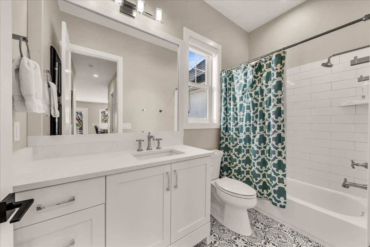 Contemporary bathroom featuring a white vanity with integrated sink, a rectangular mirror, and a three-light fixture