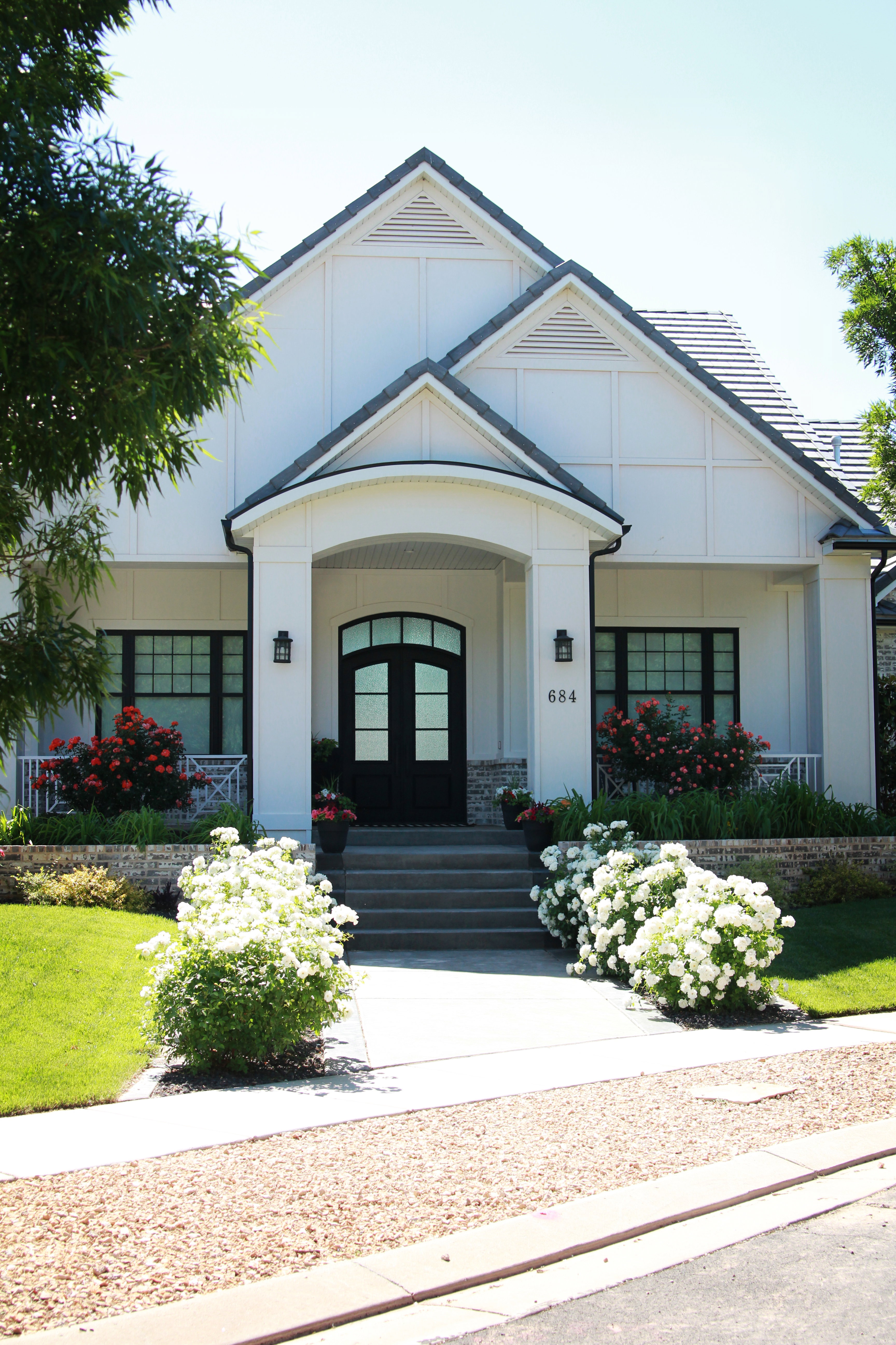 Modern farmhouse exterior with a prominent arched entry and black double doors