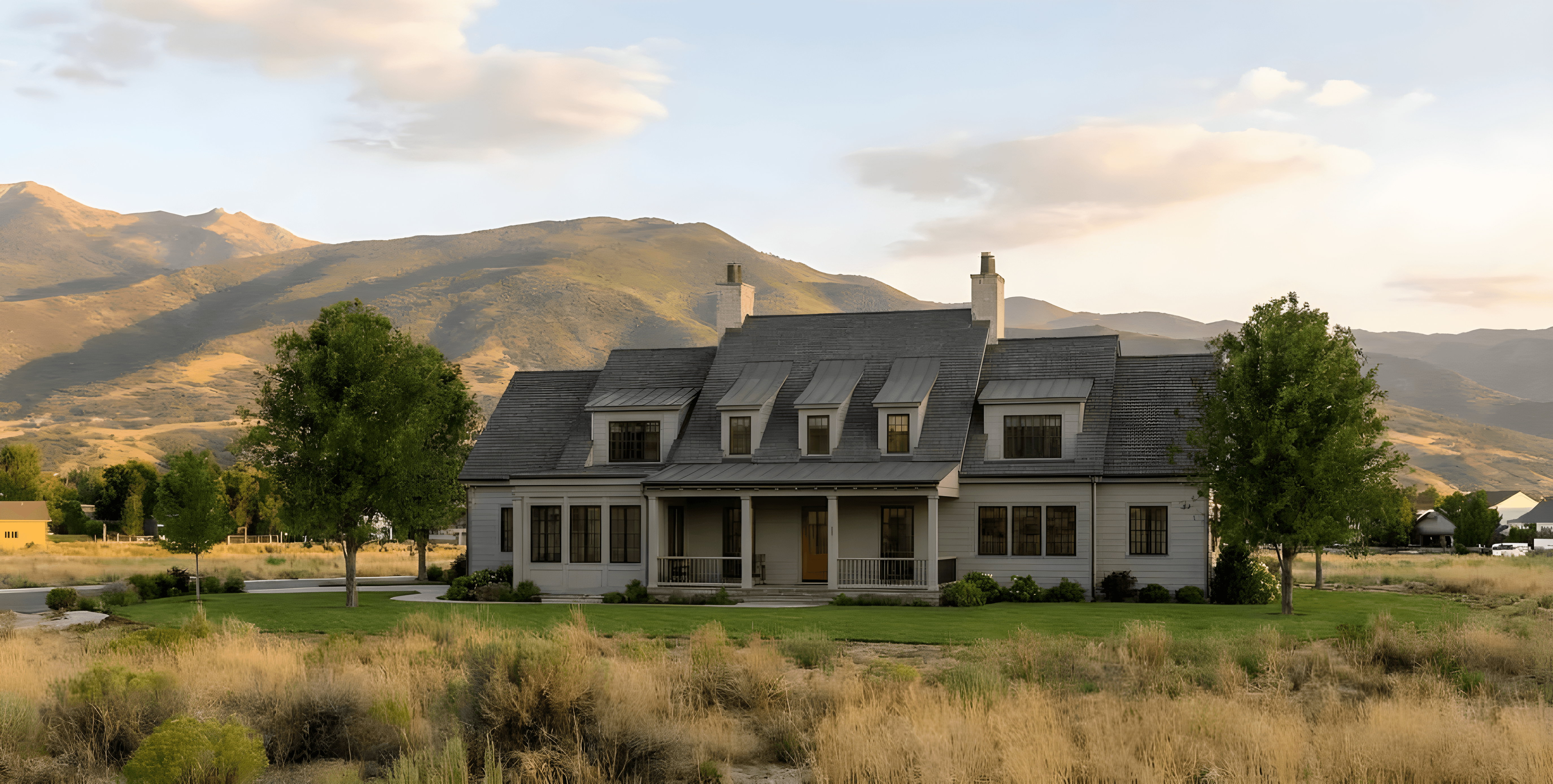 Rendering. Farmhouse-style residence featuring light gray siding, a dark gray shingled roof, multiple dormer windows, a covered front porch, and chimneys