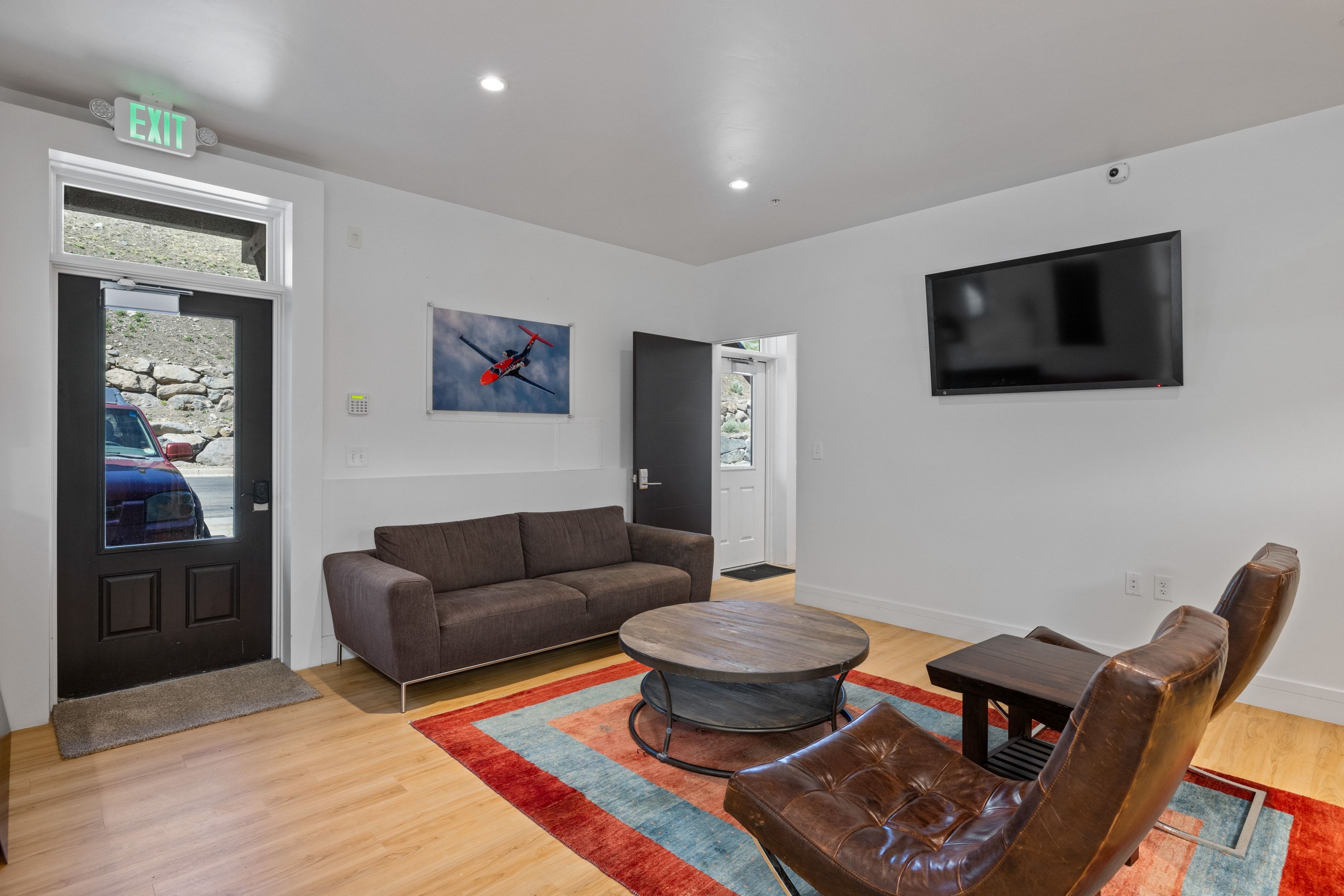 Lounge area with light wood-finish flooring, recessed lighting, and a wall-mounted flat-screen television