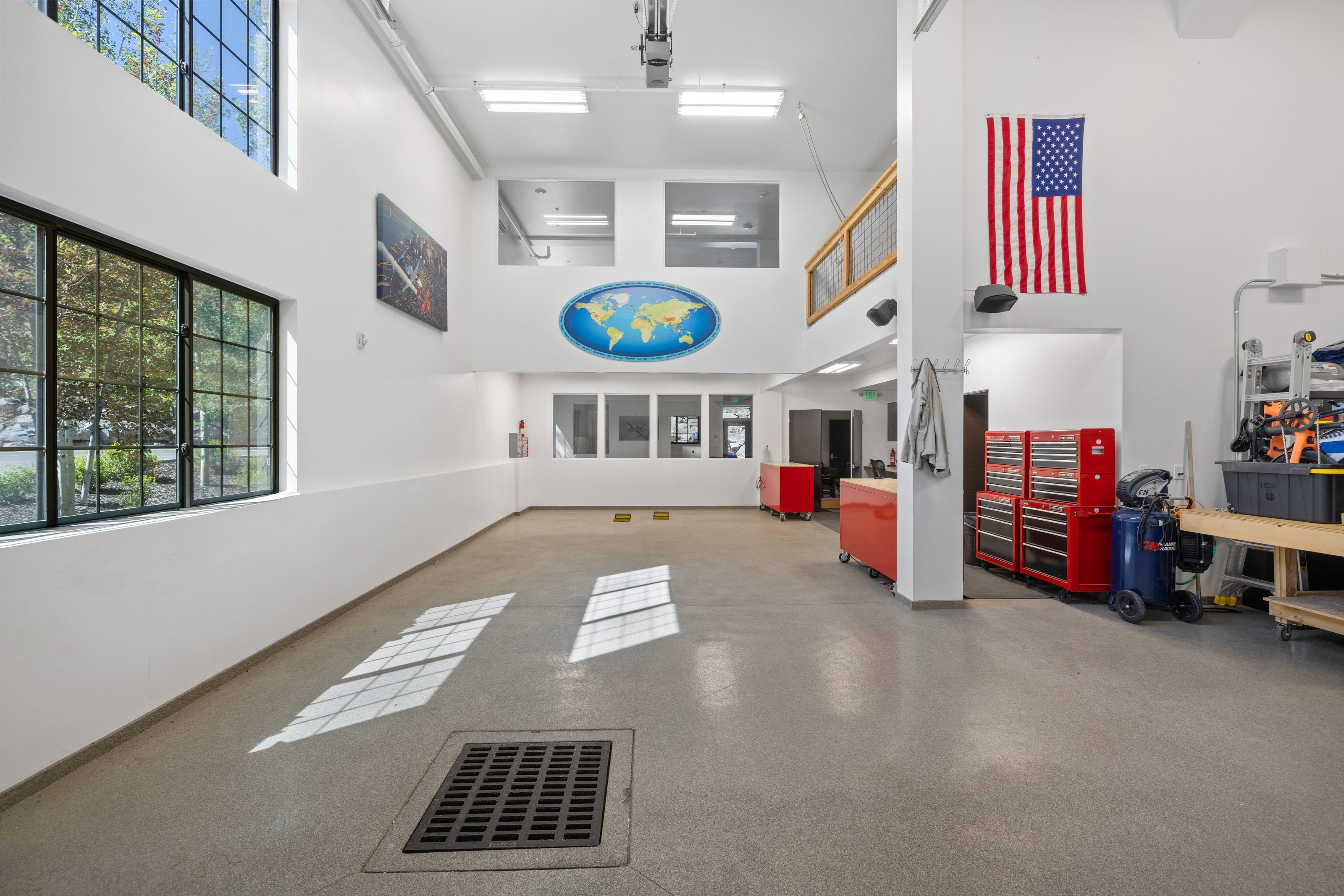 Spacious multi-purpose room featuring high ceilings with upper windows, large gridded windows, light-colored flooring, and a mezzanine balcony