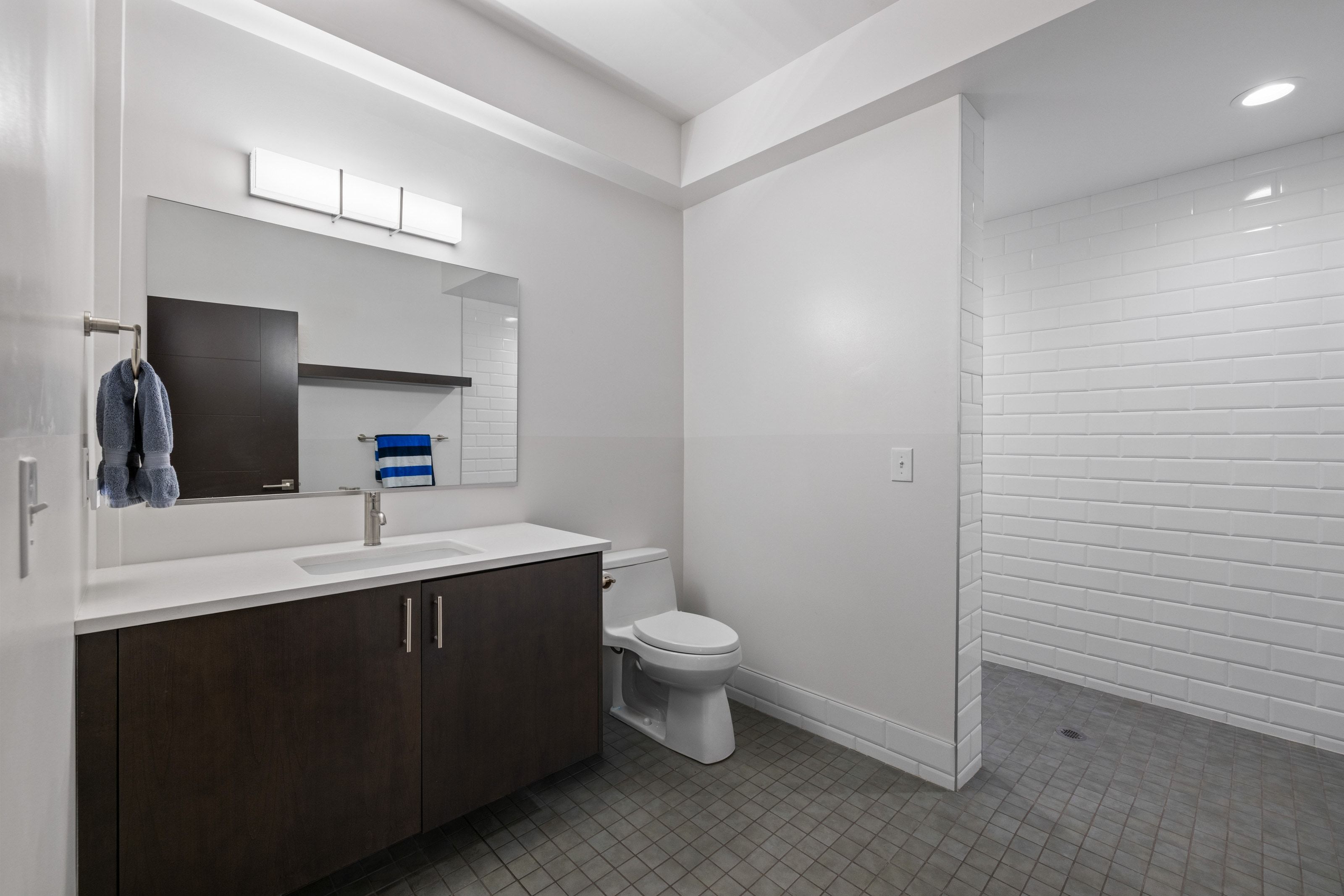 Bathroom featuring a dark wood-finish vanity with a white countertop, an undermount sink, and a rectangular mirror