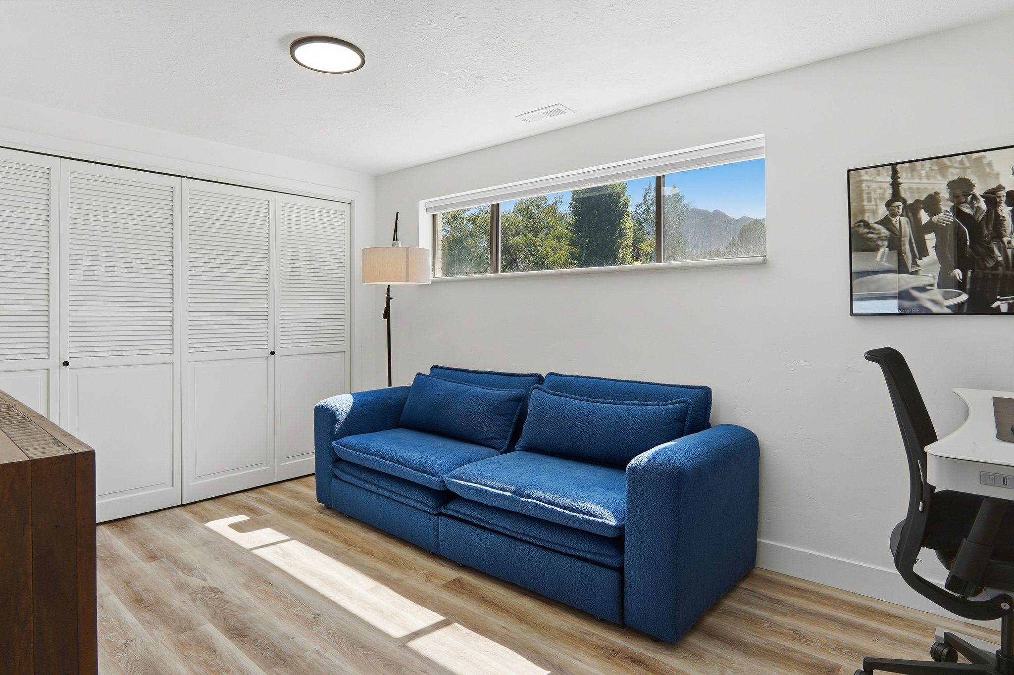 White louvered bi-fold closet doors, wood-finish flooring, and a flush-mount ceiling light fixture