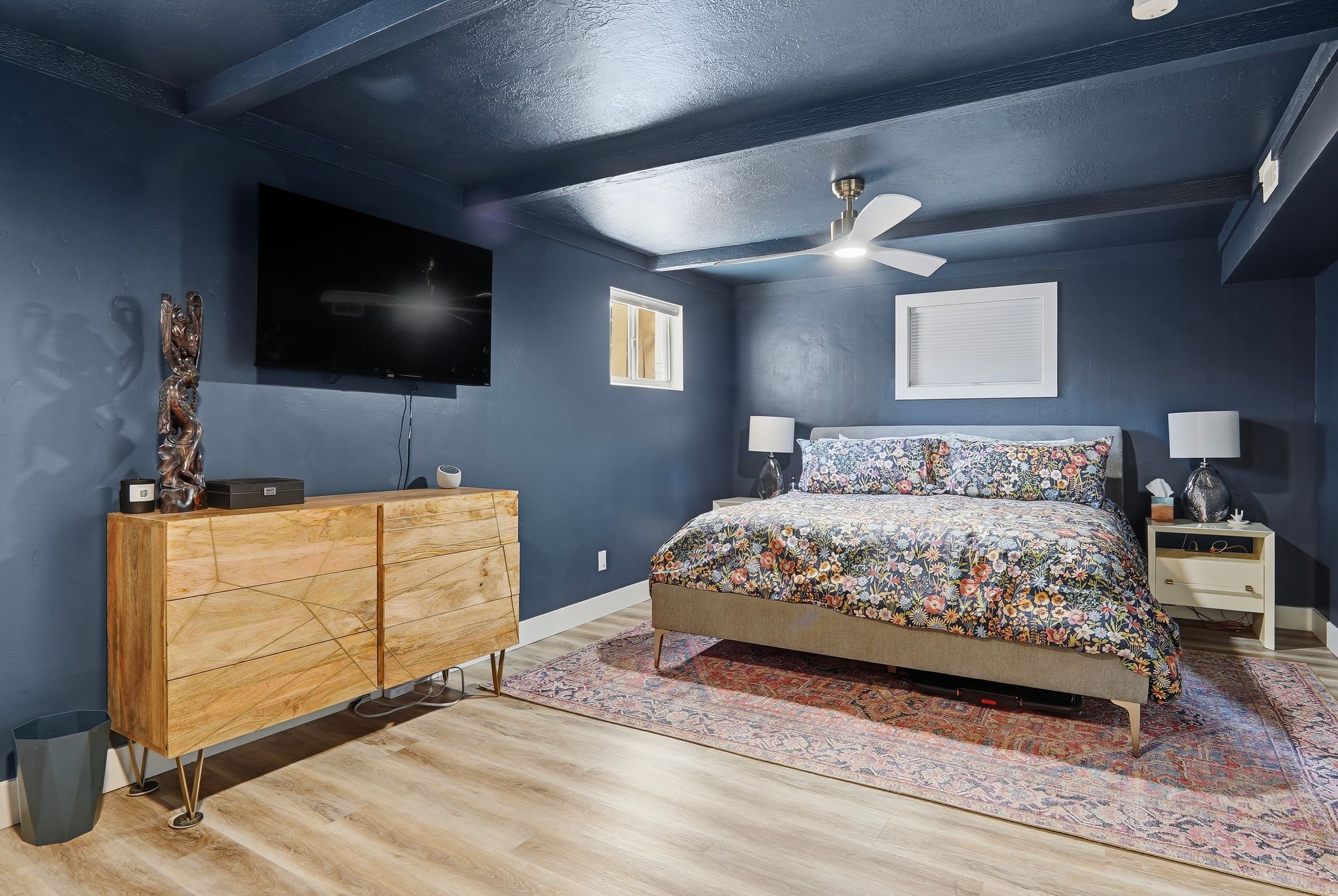 Bedroom featuring a dark blue ceiling with exposed beams, wood-finish flooring, and a ceiling fan