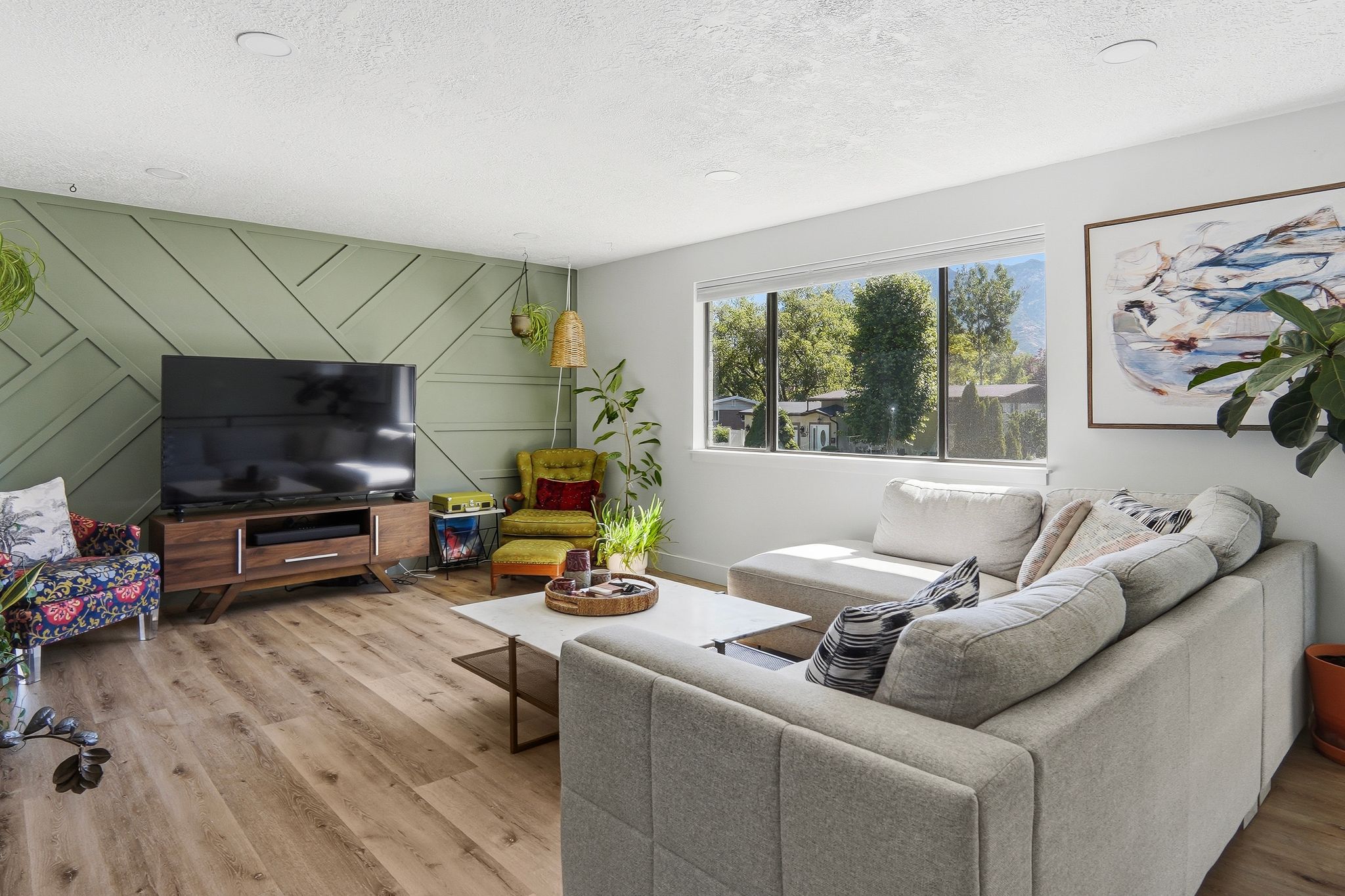 Living space featuring wood-finish flooring, a decorative accent wall with geometric paneling, and recessed lighting