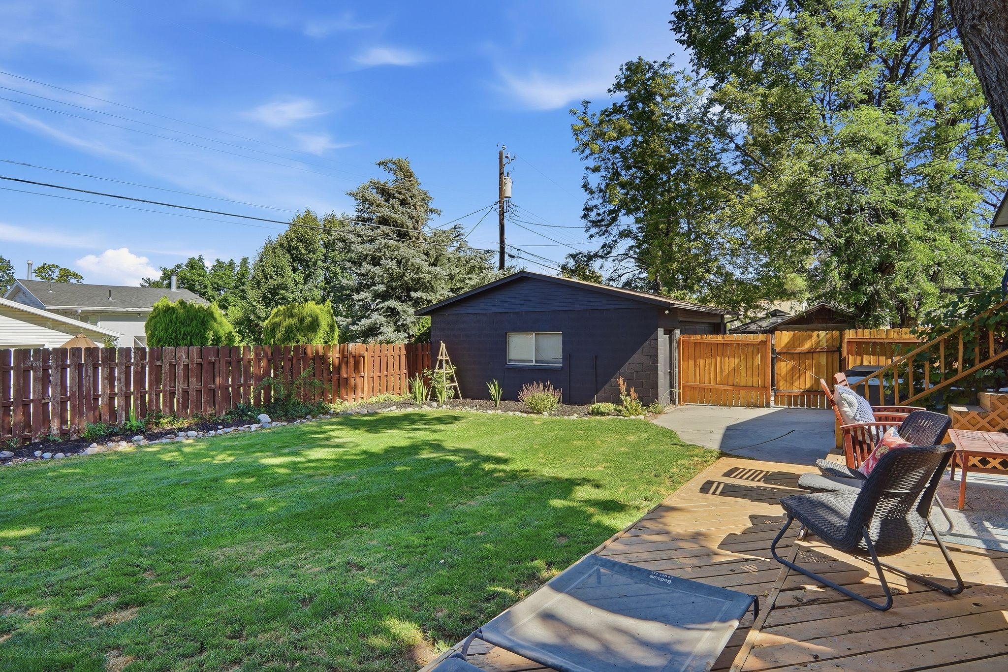 Expansive backyard featuring a wood deck, concrete patio, and manicured lawn