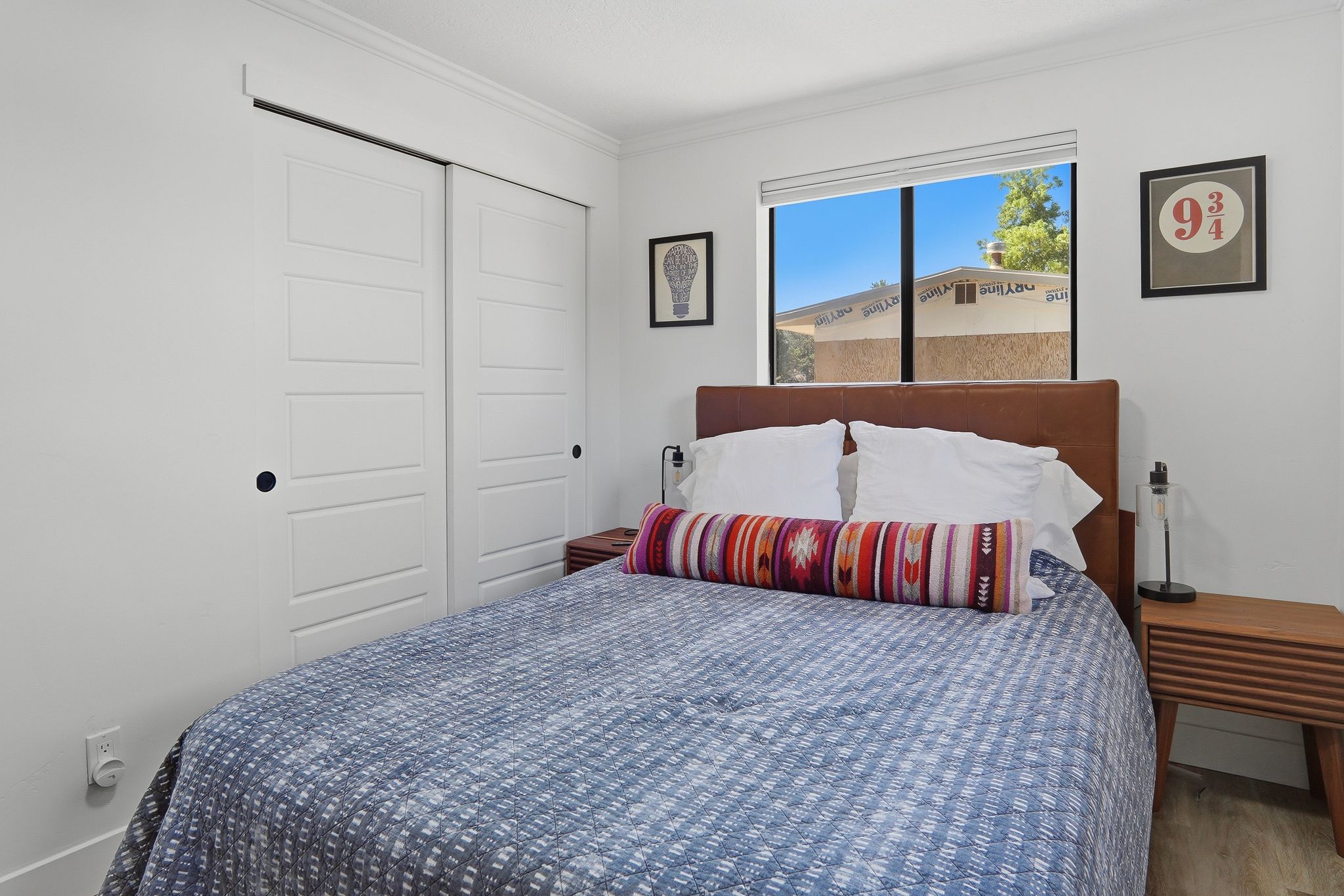 Bedroom featuring a large window, white walls, and wood-finish flooring