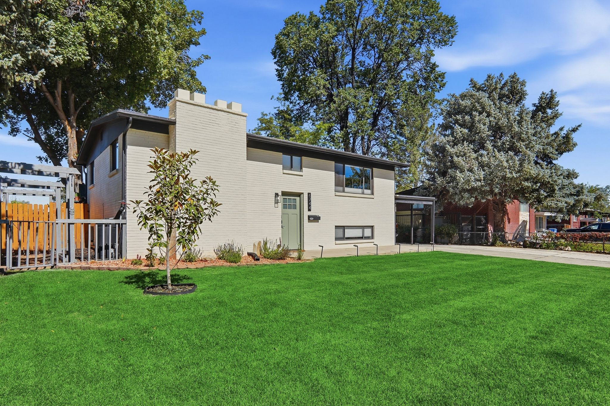 Split-level residence featuring a light-colored brick exterior, a castle-style chimney, and a mint green entry door