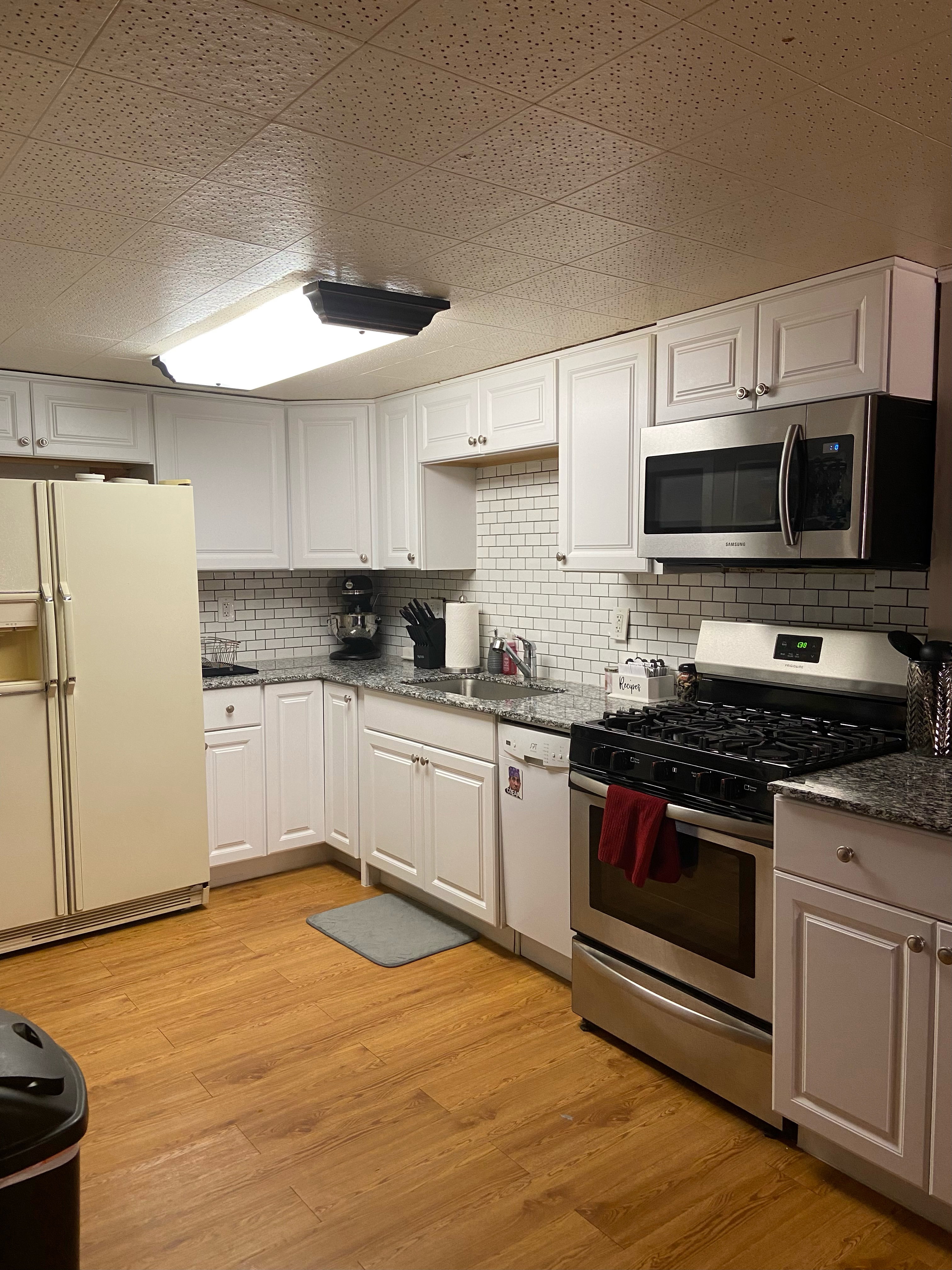 Kitchen featuring white cabinetry, subway tile backsplash, and wood-finish flooring