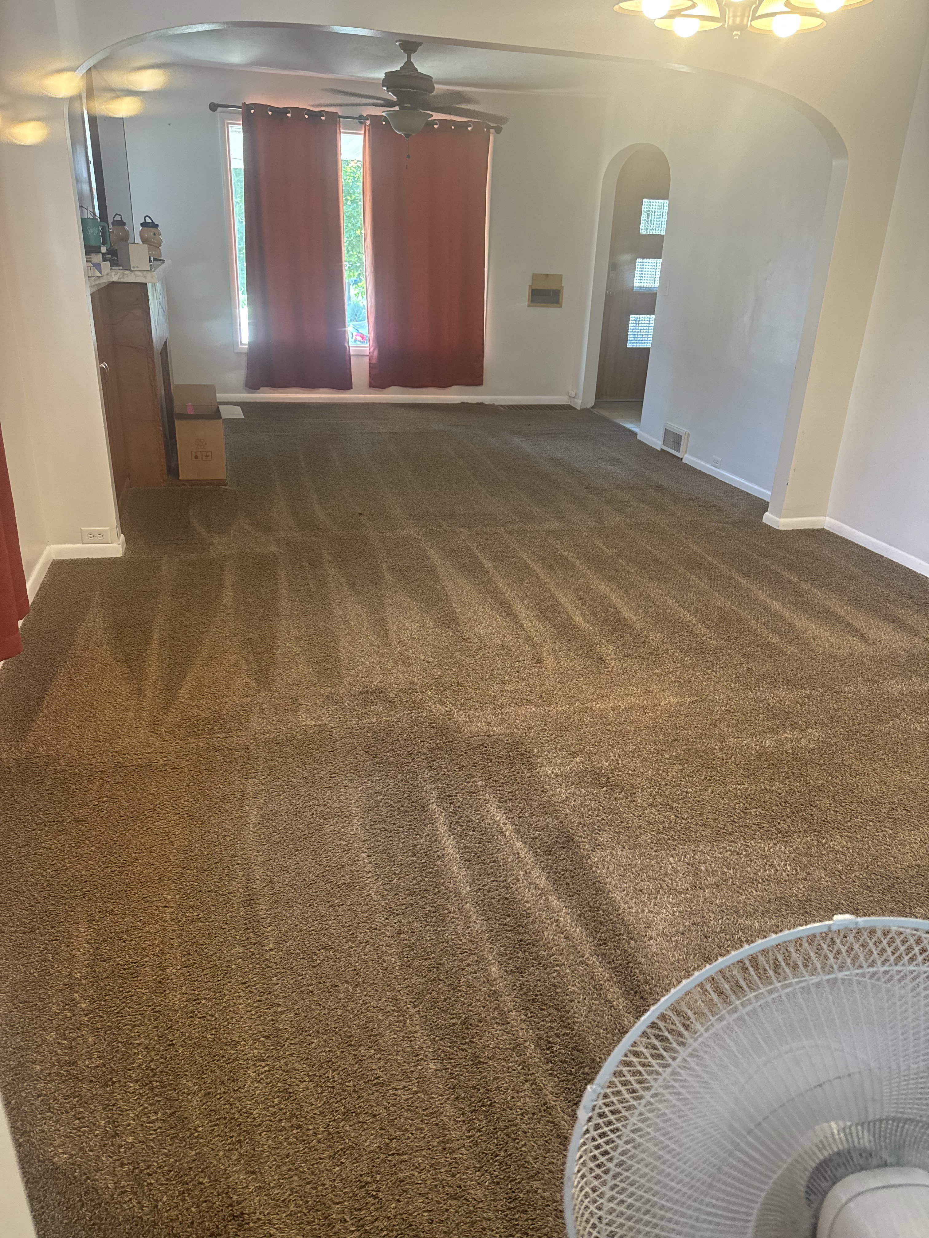 Spacious room featuring broadloom carpet, an arched entryway, and a ceiling fan