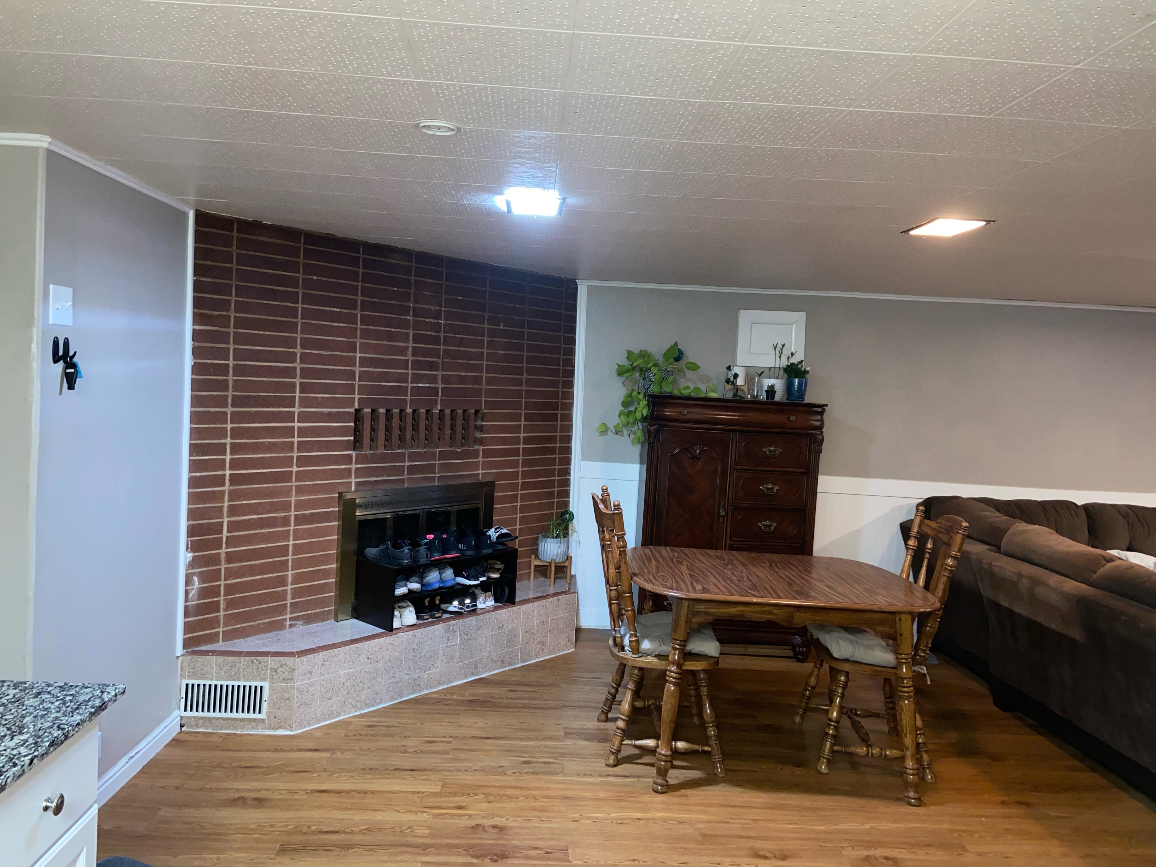 Room featuring wood-finish flooring and a brick-patterned fireplace with a brass firebox