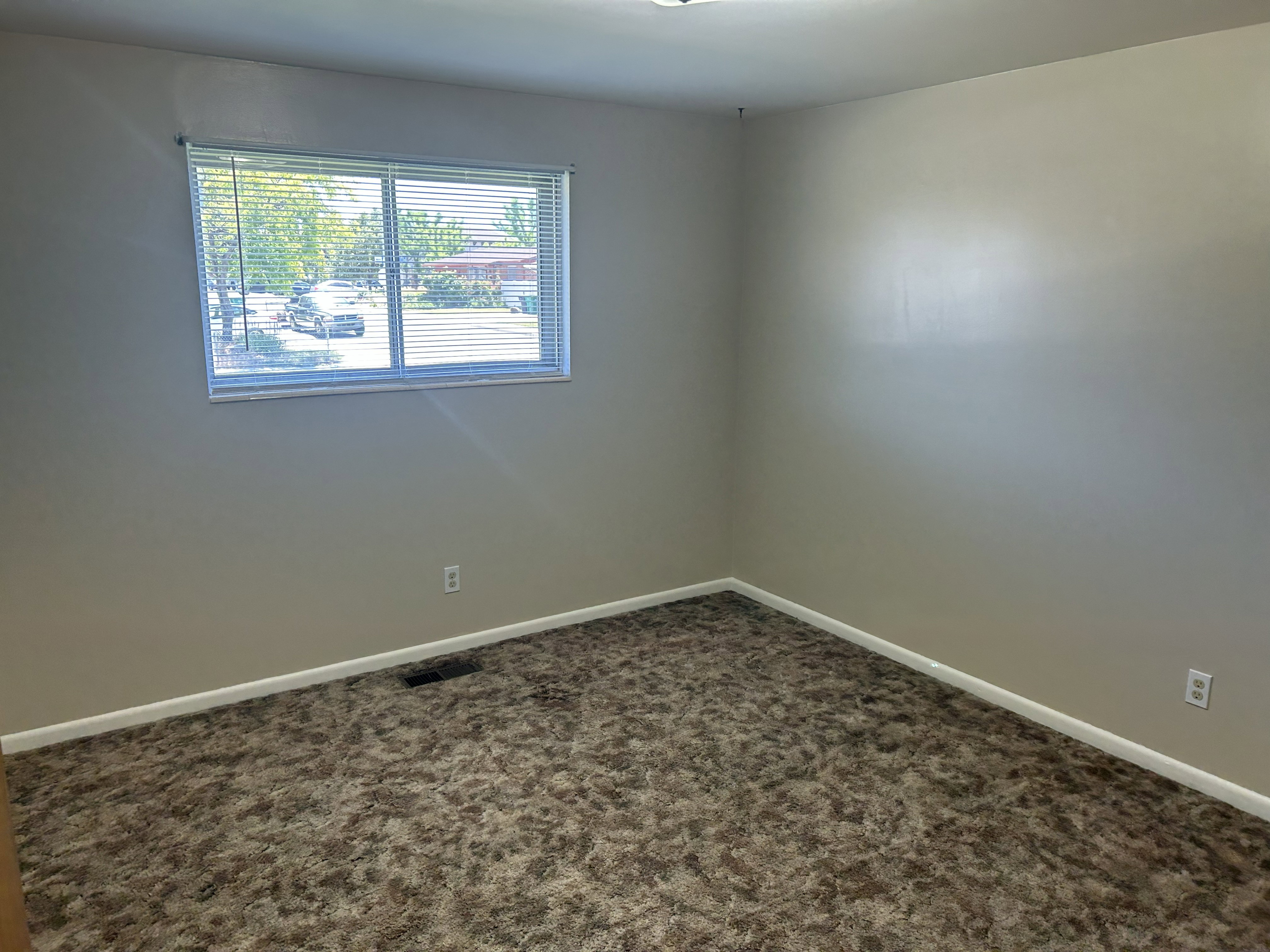 Room featuring a window with horizontal blinds, neutral wall paint, and patterned carpet flooring
