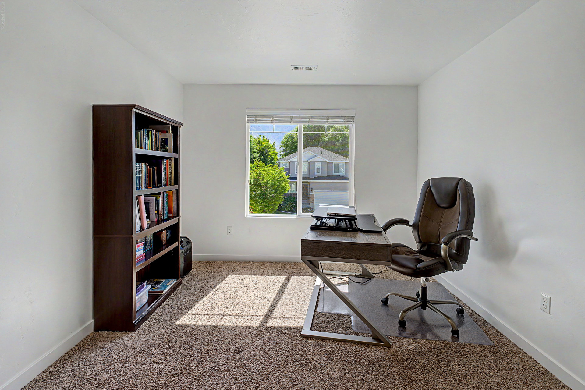 Carpeted room featuring white walls, a large window with horizontal blinds, and white baseboards