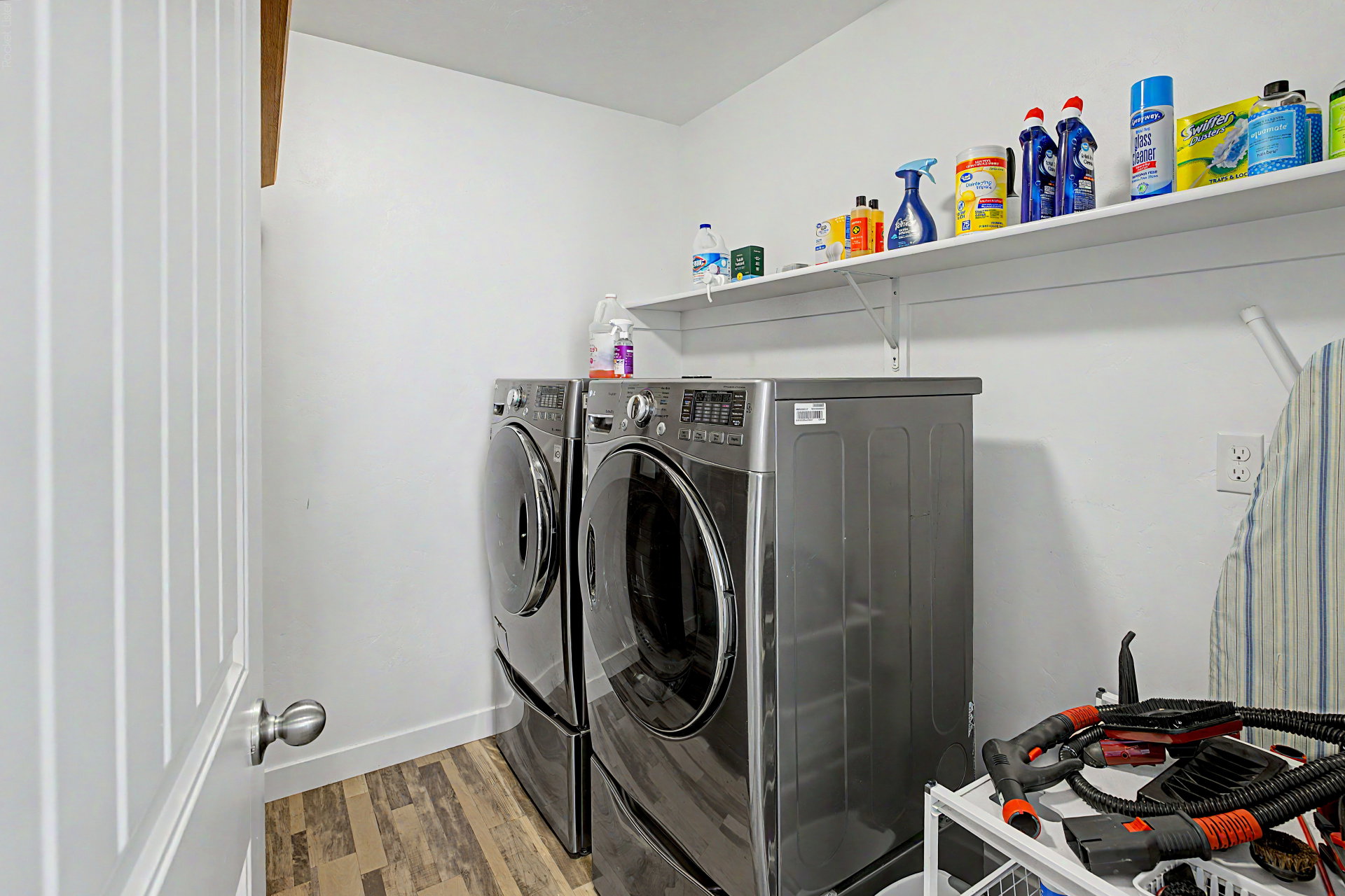 Dedicated laundry area featuring wood-finish flooring, white walls, and a convenient wall-mounted shelf