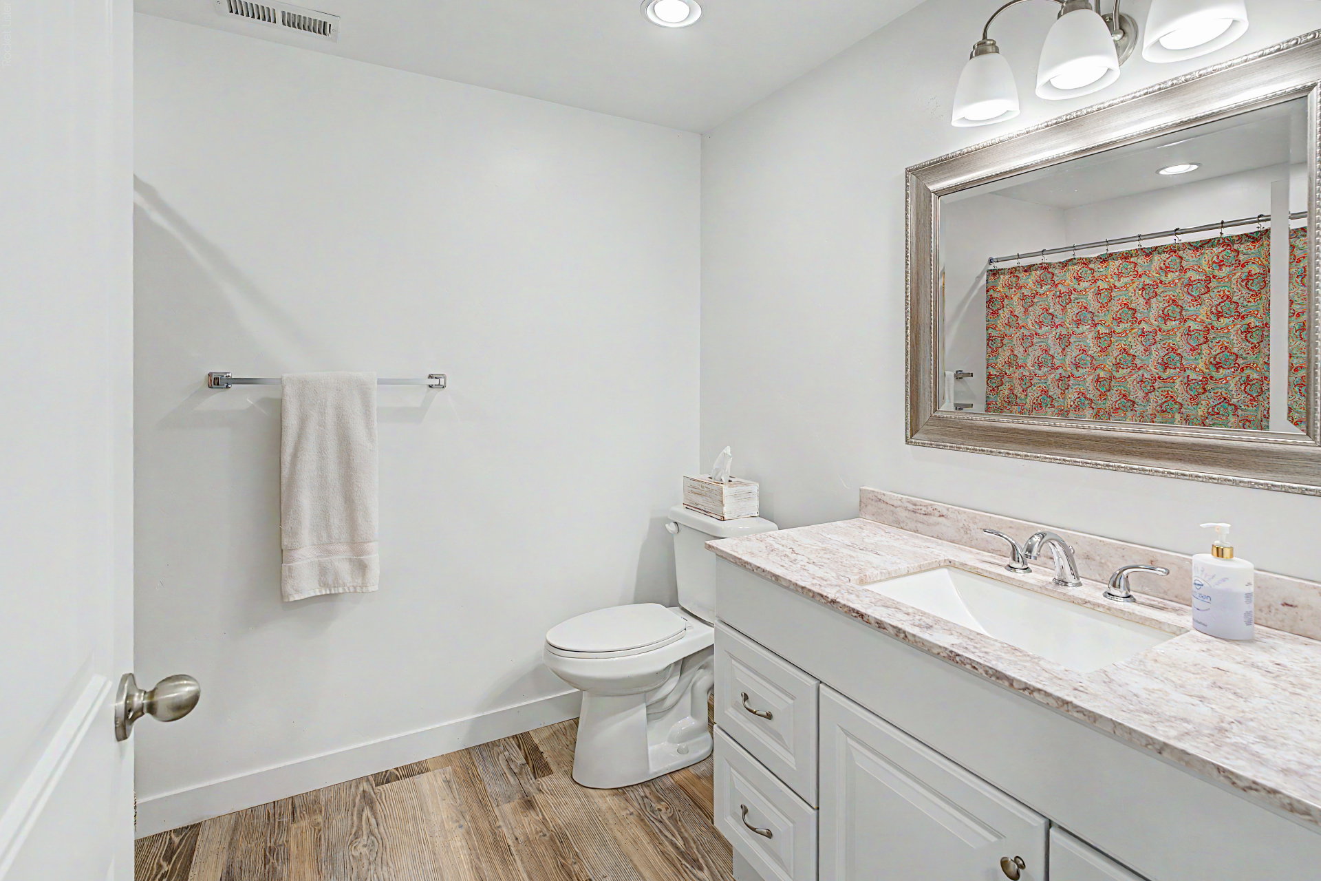 Bathroom featuring a white vanity with an undermount sink, a light-colored countertop, and wood-finish flooring