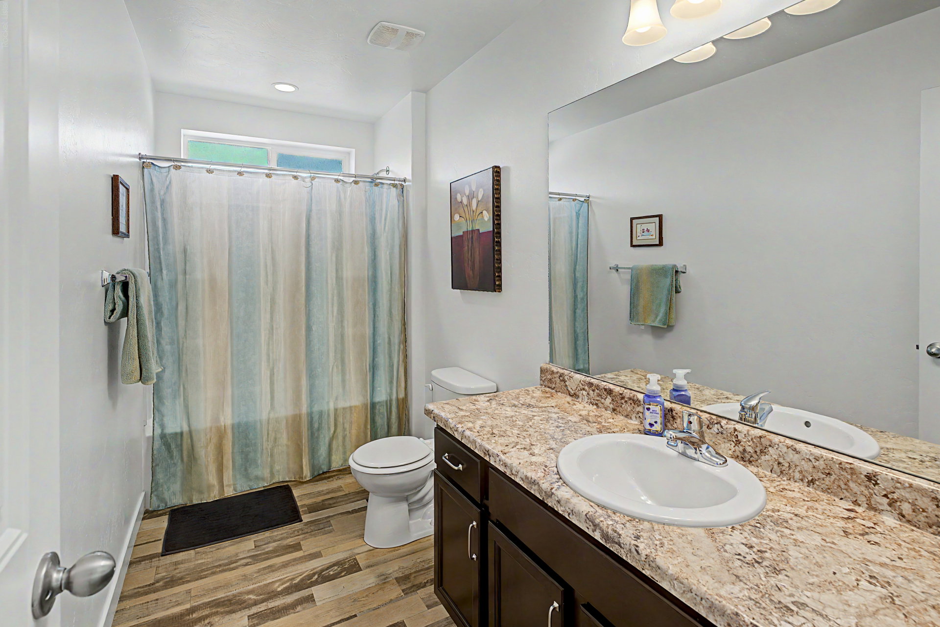 Bathroom featuring a vanity with a light-toned countertop, an undermount sink, and dark wood-finish cabinetry