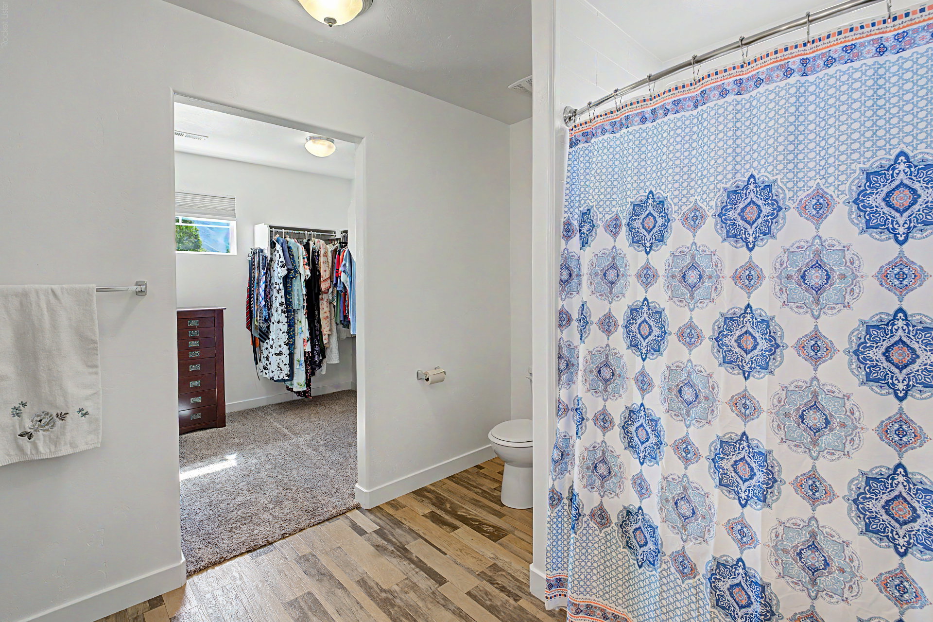 Bathroom featuring wood-finish flooring and a white toilet
