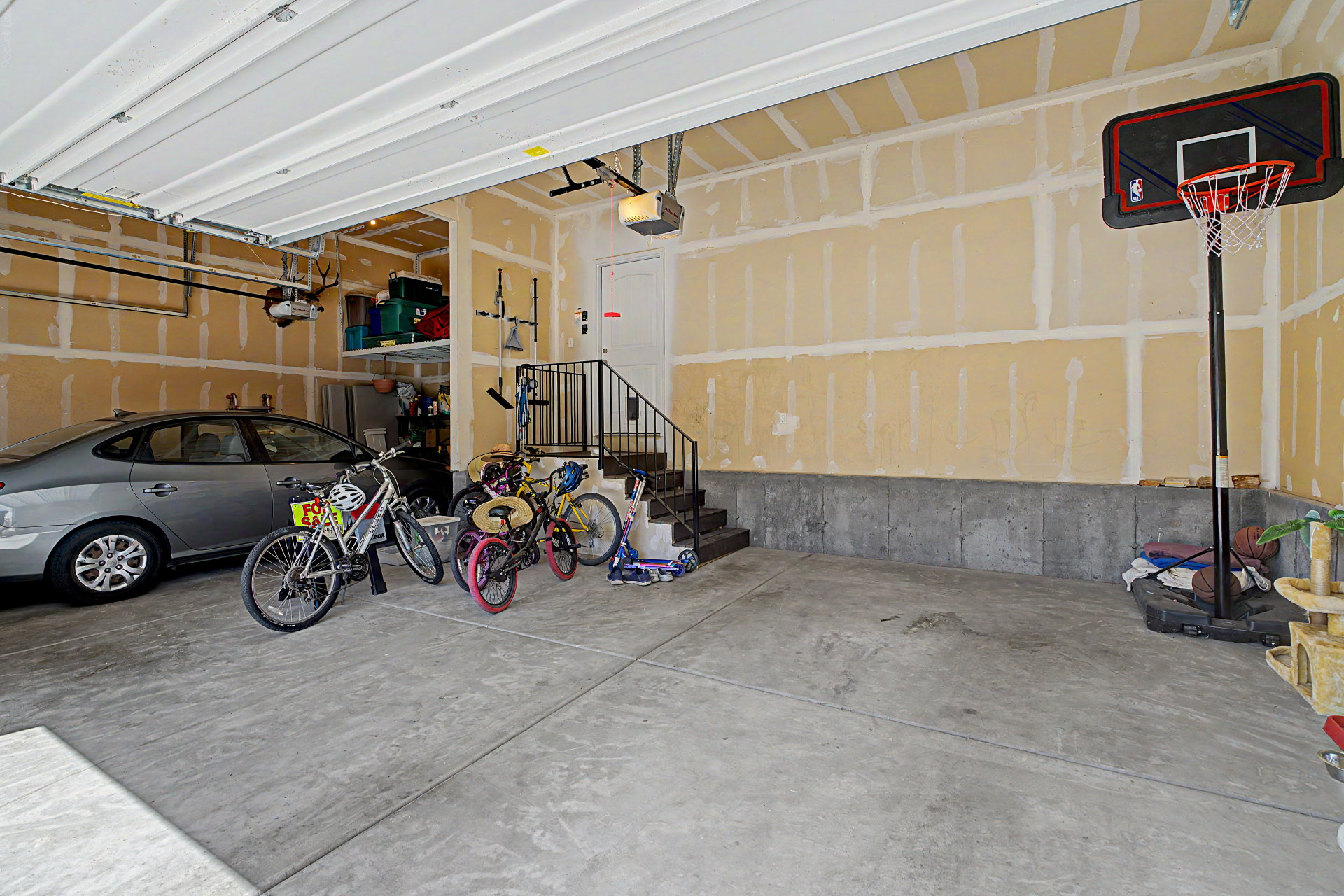 Spacious garage with a concrete floor, overhead garage door, and built-in shelving