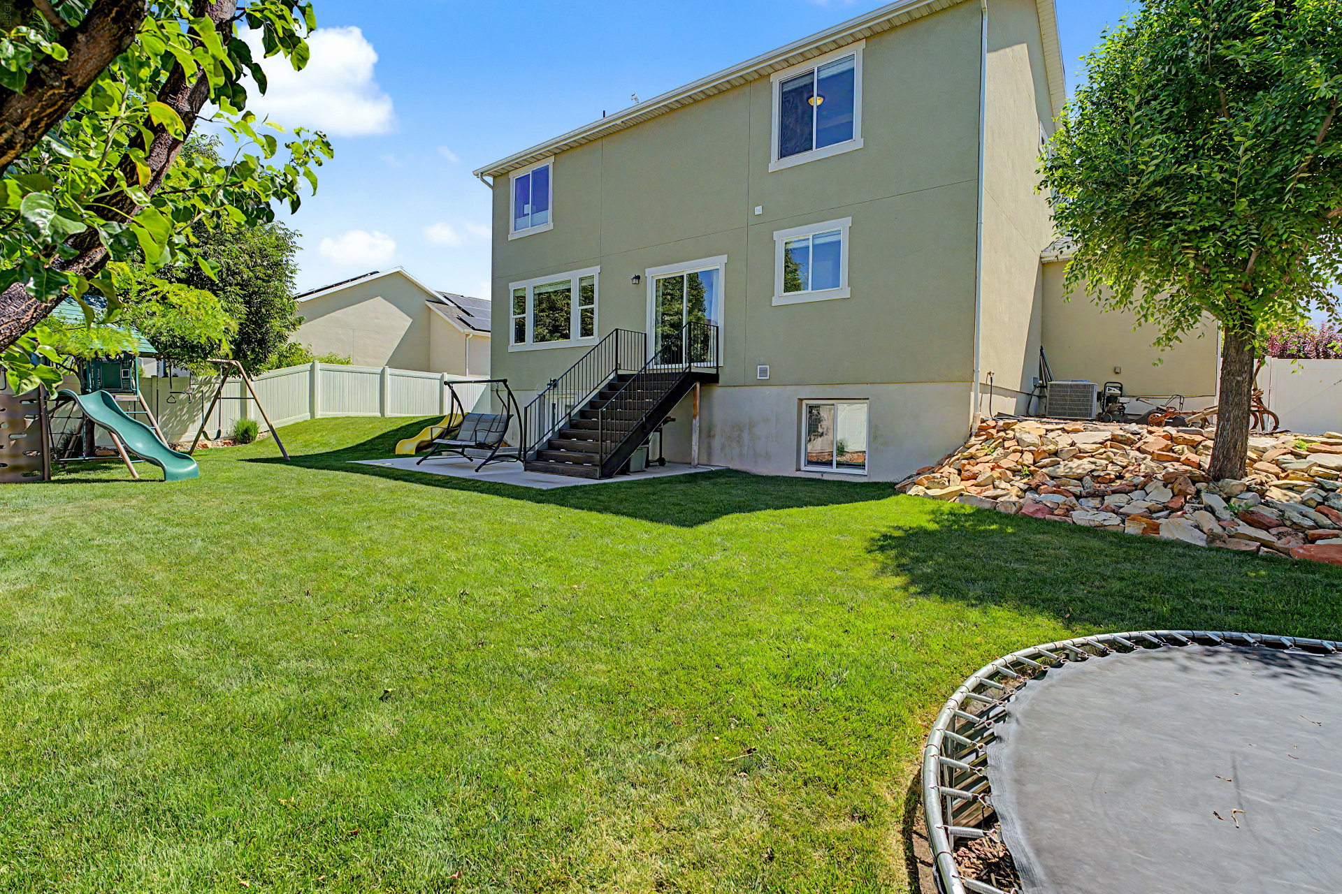 Expansive backyard featuring a lush lawn, a privacy fence, and a rock landscaping area