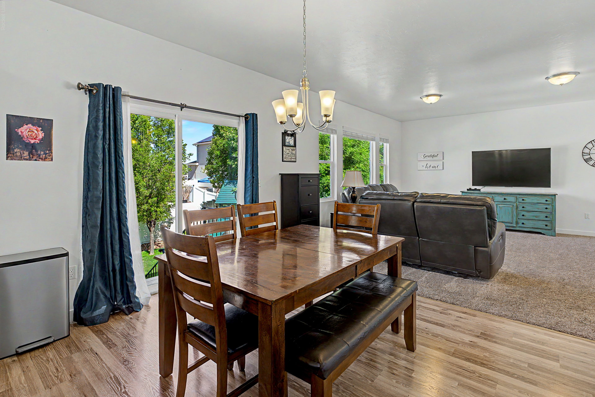 Open-concept living space with wood-finish flooring, a contemporary chandelier, recessed lighting, and large windows providing abundant natural light