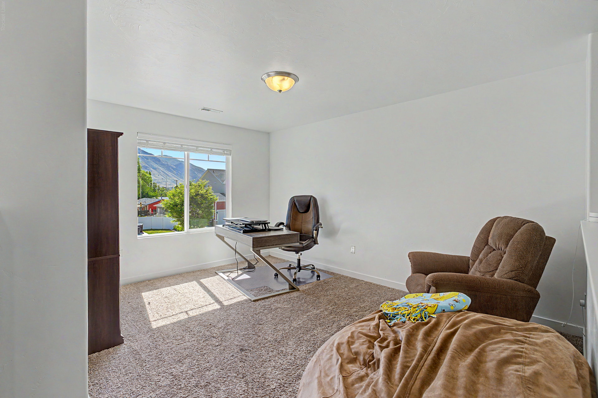 Room featuring neutral carpeting, white painted walls, and a large window with white blinds