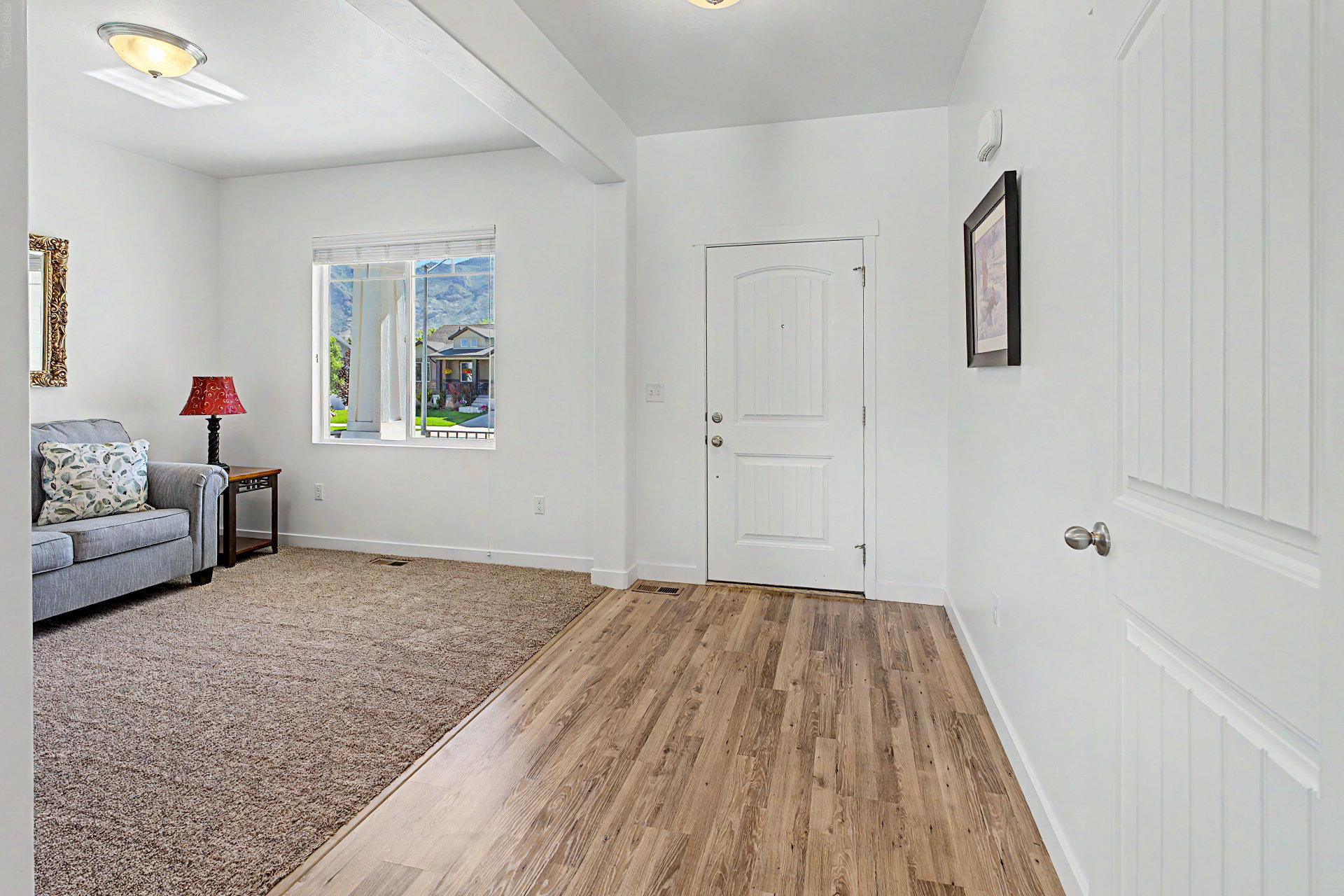 Entryway featuring wood-finish flooring, a white paneled door, and a recessed ceiling beam