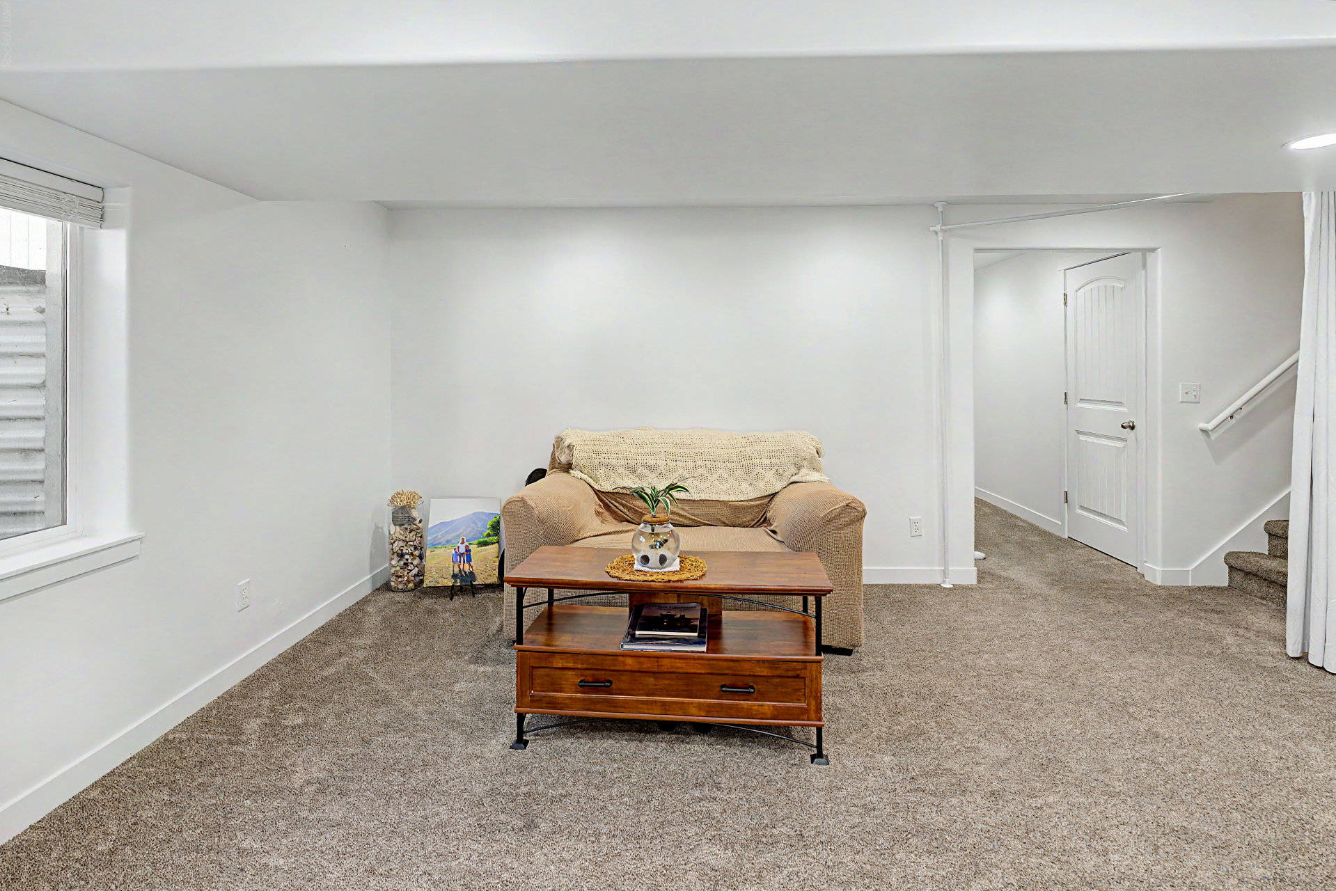 Finished basement space featuring plush grey carpeting and bright white walls