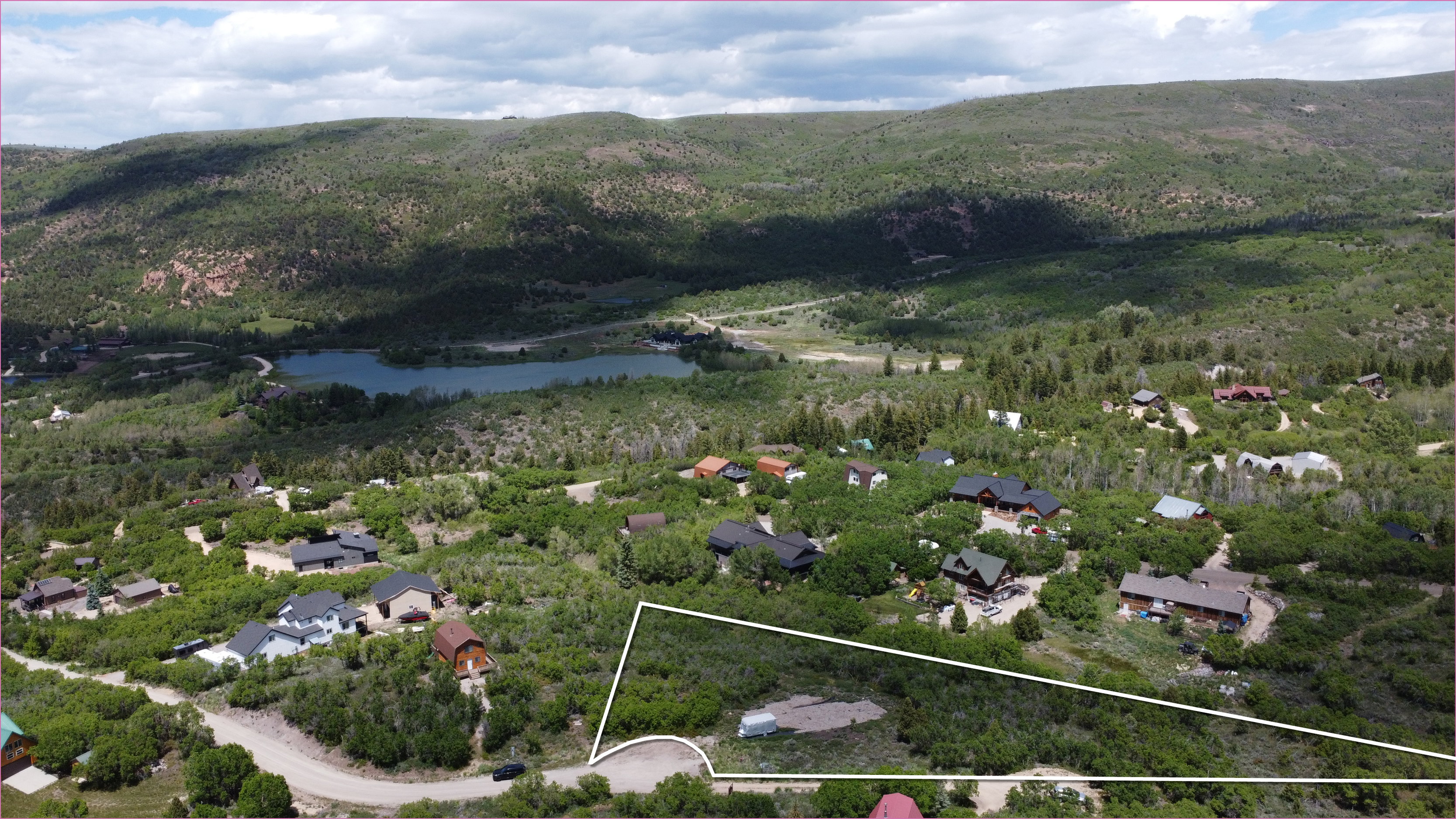 Expansive undeveloped lot featuring natural vegetation, a curved road frontage, and a partially cleared area