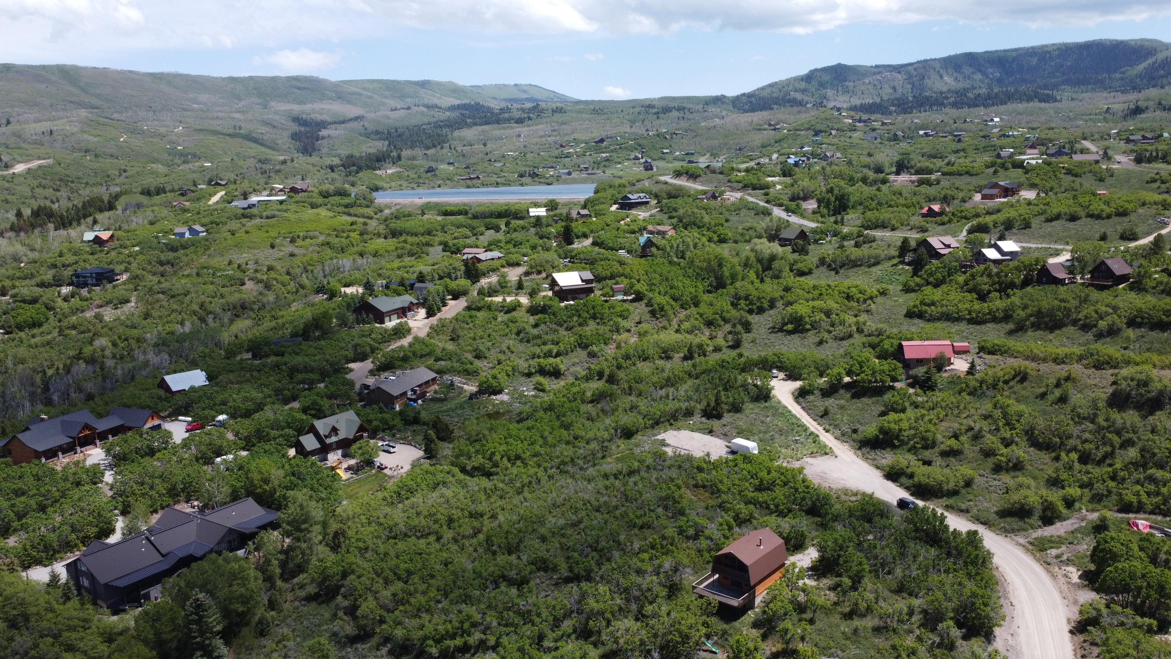 Elevated aerial perspective showcasing a residential community nestled within a mountainous, verdant landscape