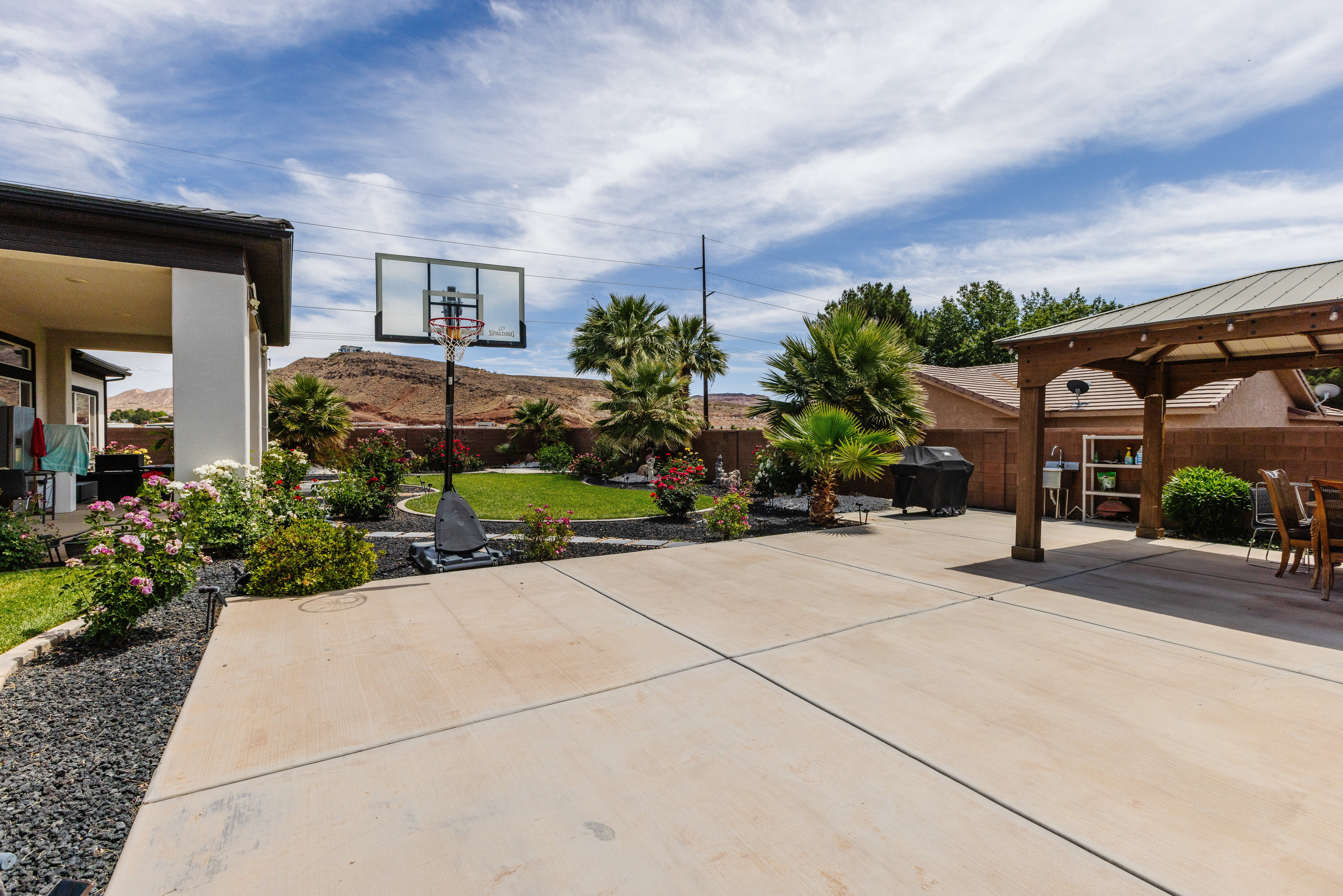Expansive concrete patio with a covered outdoor dining area and integrated landscaping