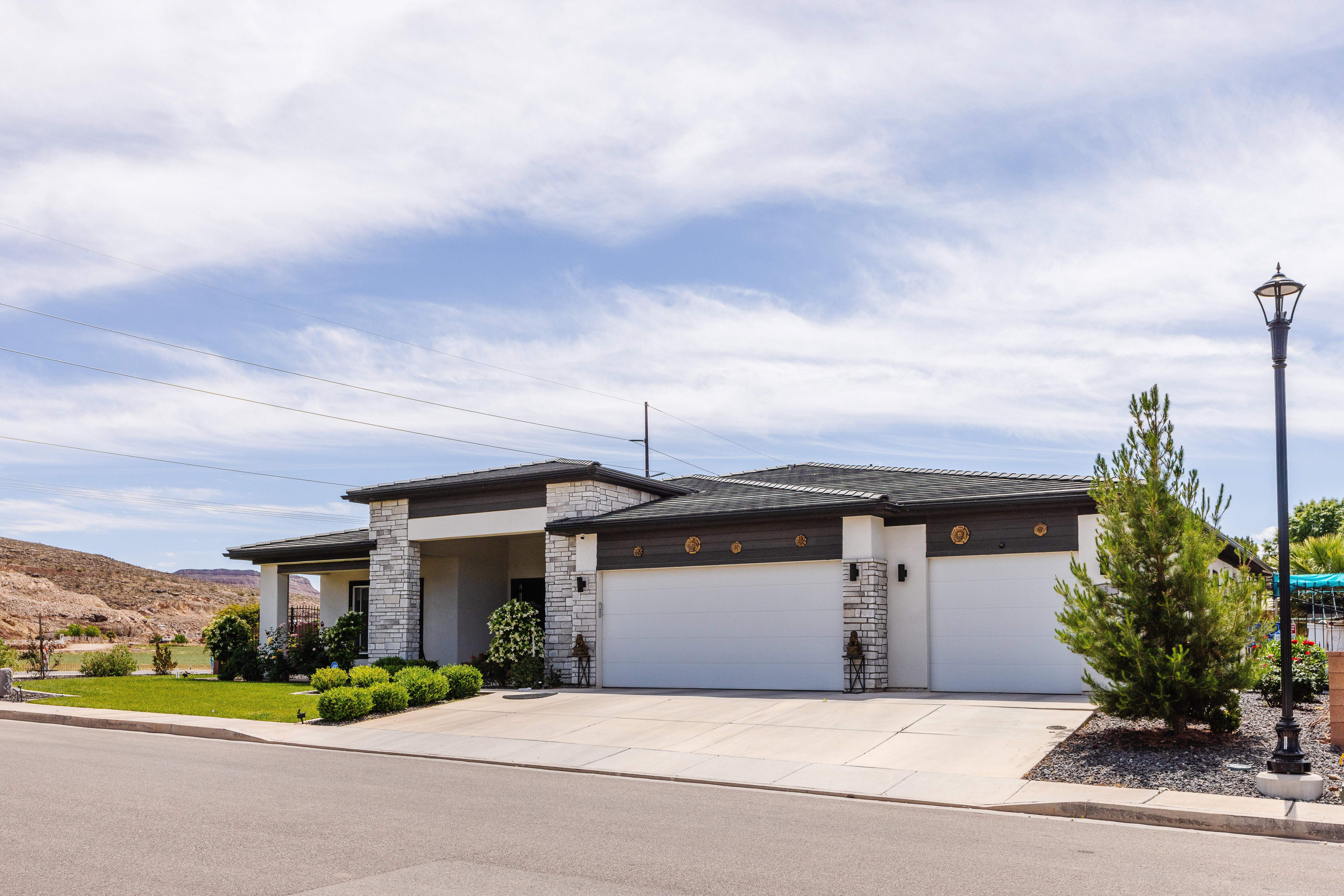 Contemporary ranch-style exterior featuring a stone and stucco facade, a dark shingle roof, and a concrete driveway