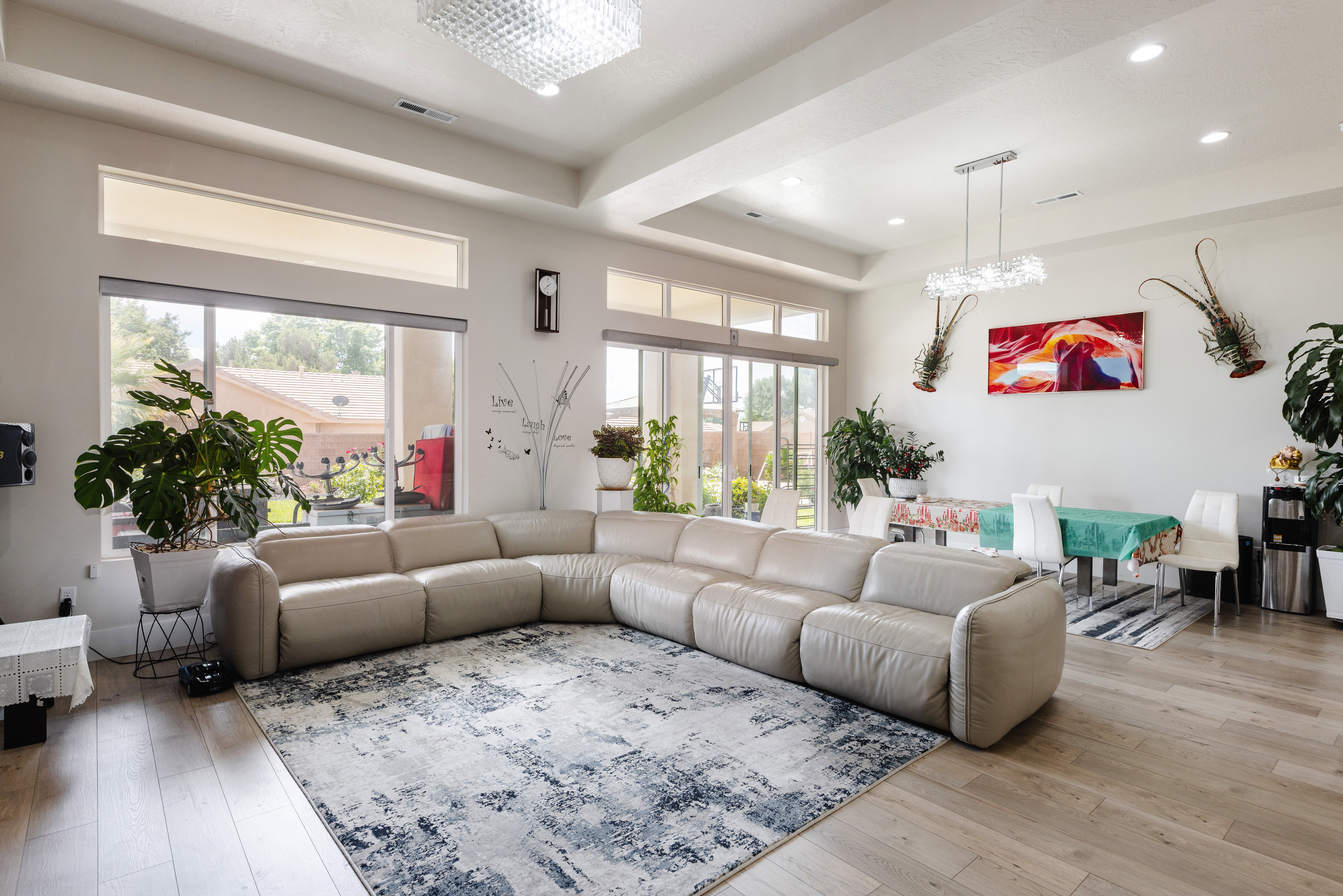 Spacious living area featuring wood-finish flooring, high ceilings with recessed lighting, and large windows with transom architectural details