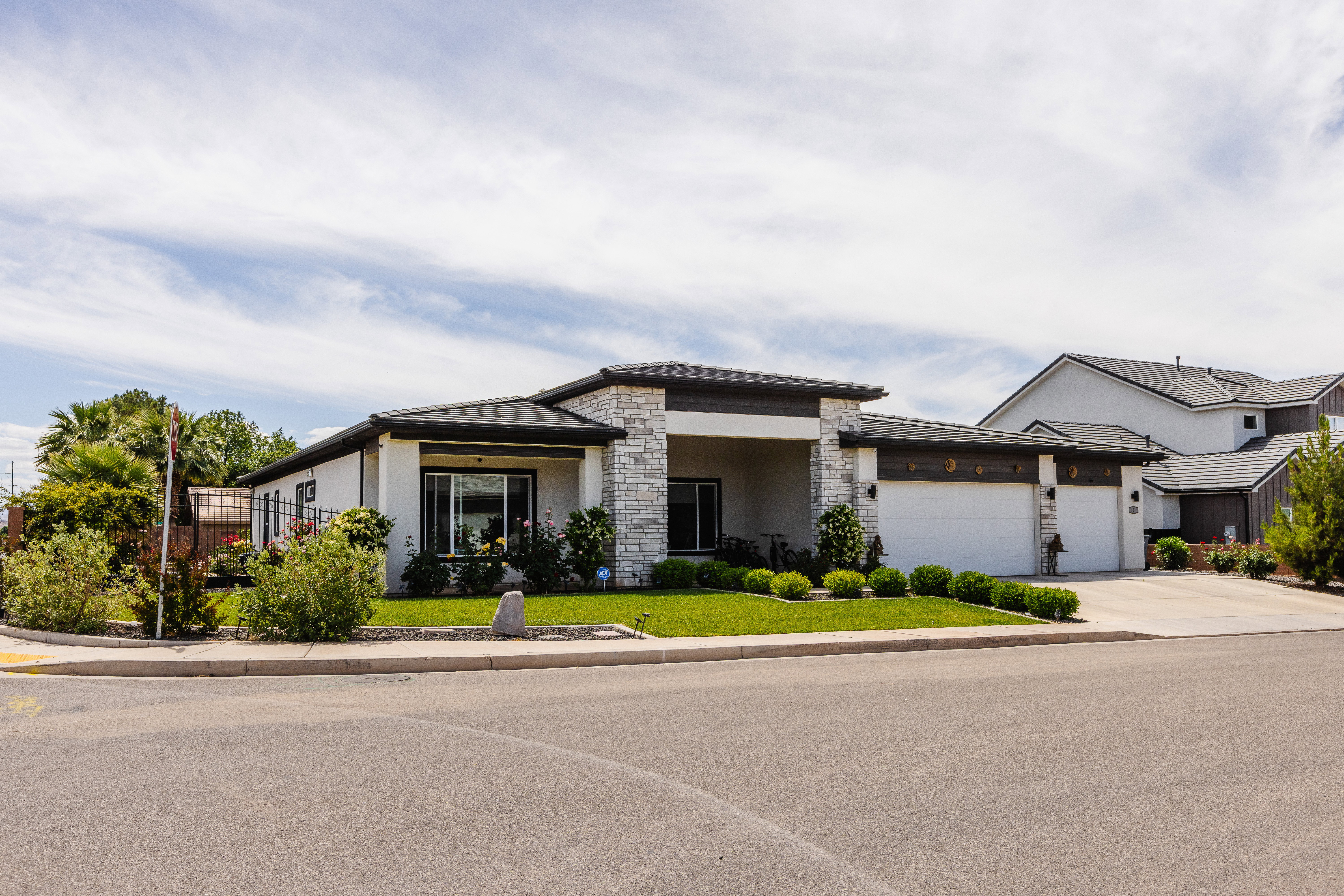 Contemporary stucco and stone-clad exterior with a dark shingled roof