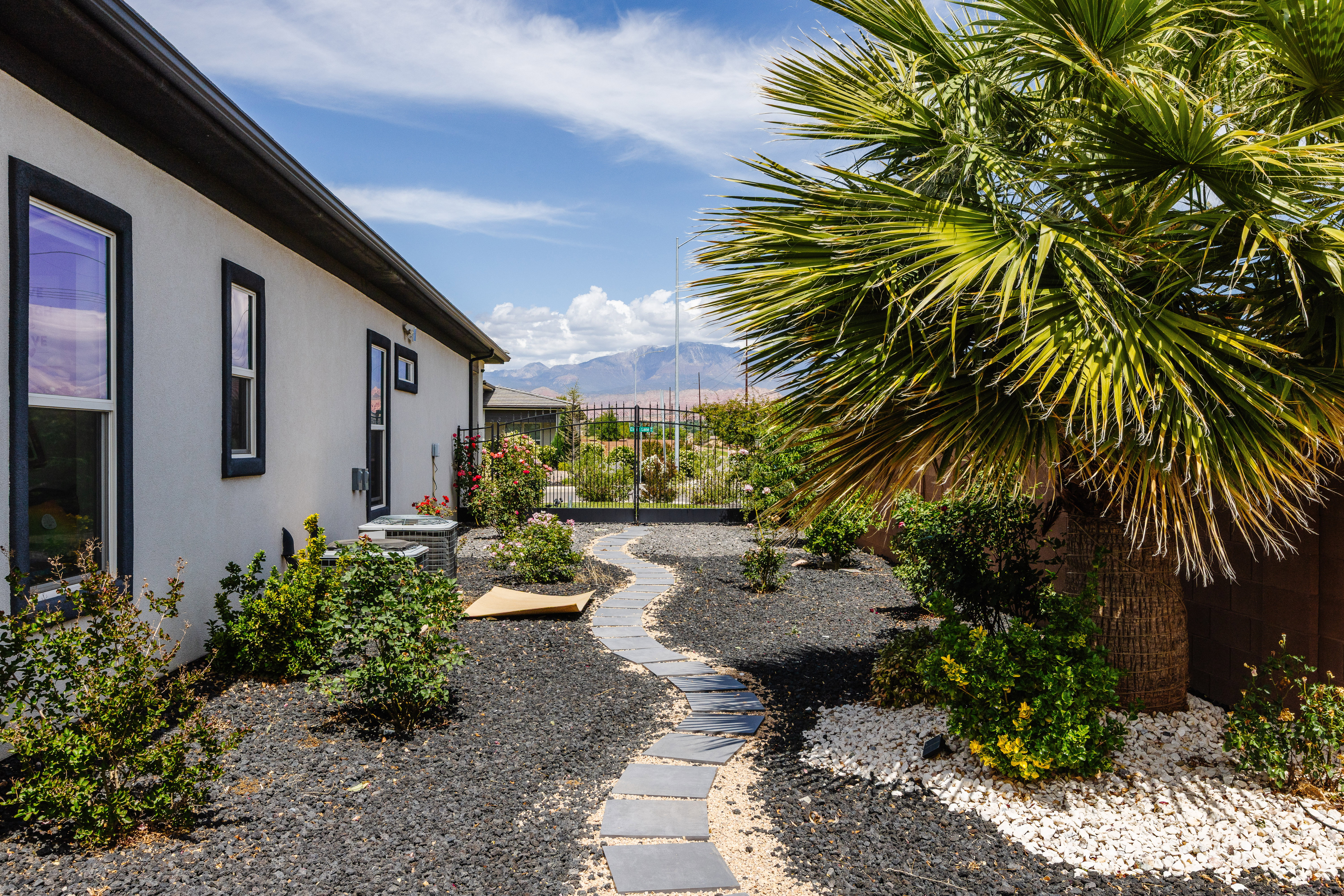 Stucco exterior with contrasting trim, featuring a stone pathway through landscaped grounds