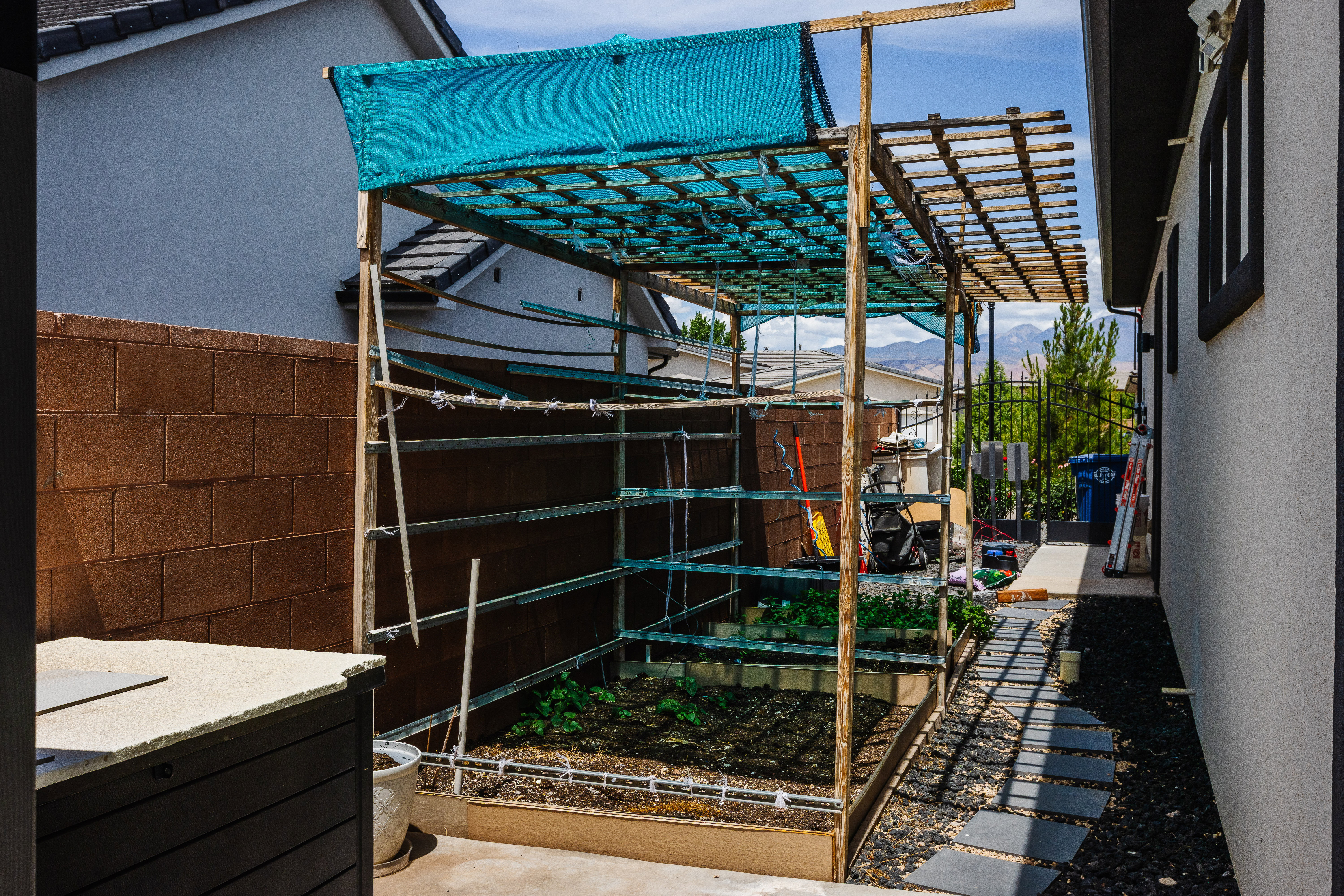 Enclosed planter bed with an overhead trellis structure and partial shade covering